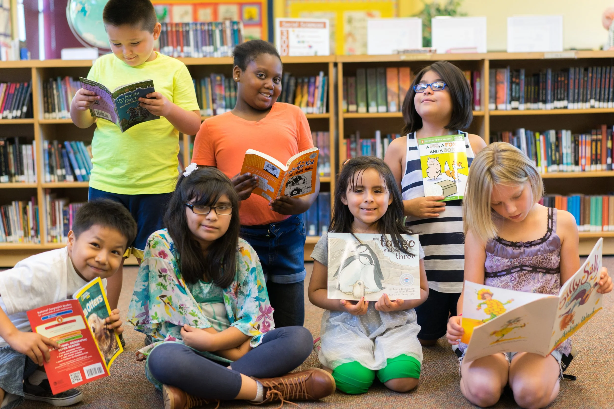 Diverse group of children reading books together in a colorful library