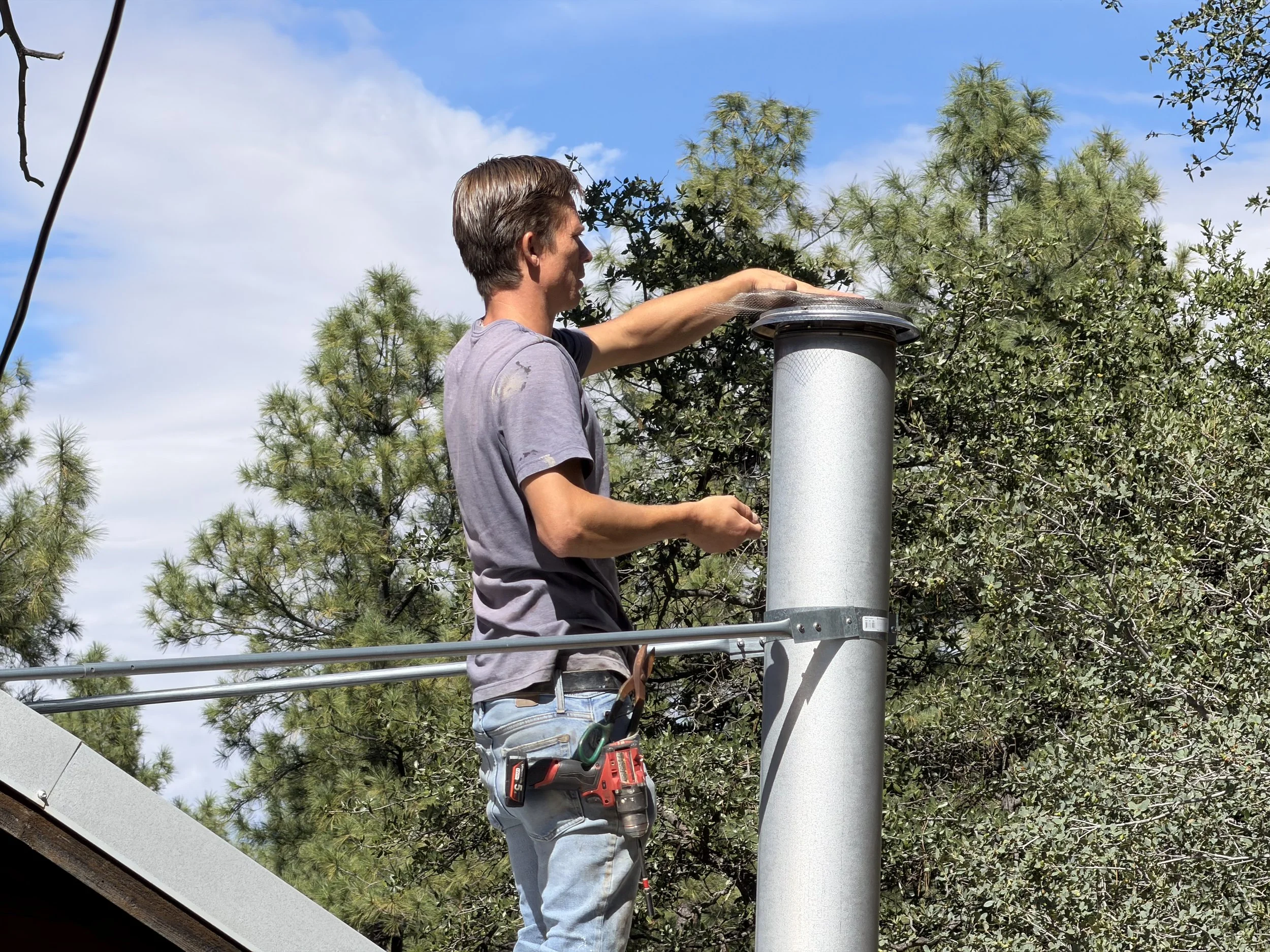 Installing metal mesh on a chimney cap to help prevent sparks and keep pests out during a Prescott, Arizona home improvement project.