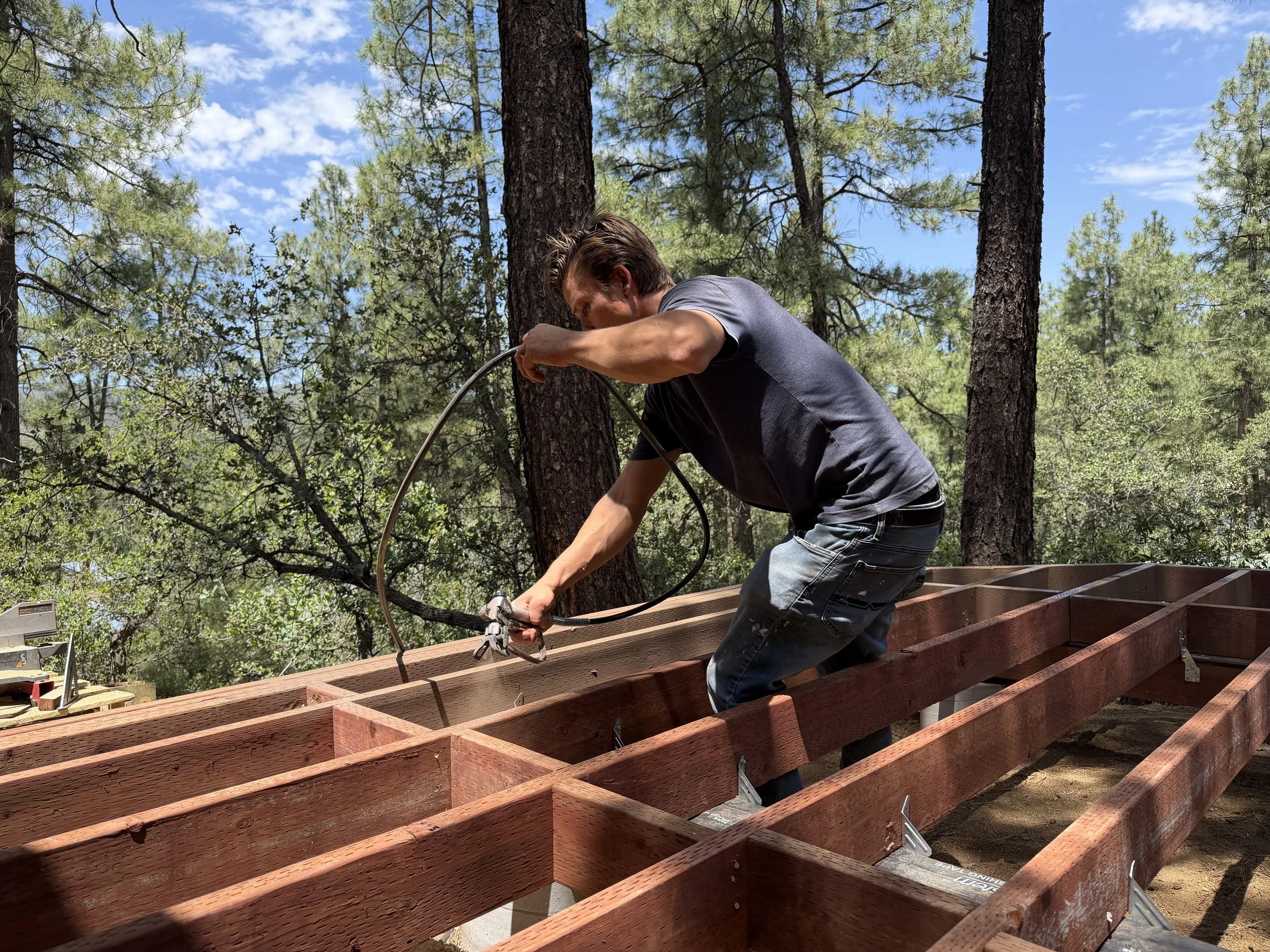 Applying protective paint to deck framing before Trex board installation during a Prescott, Arizona deck project.