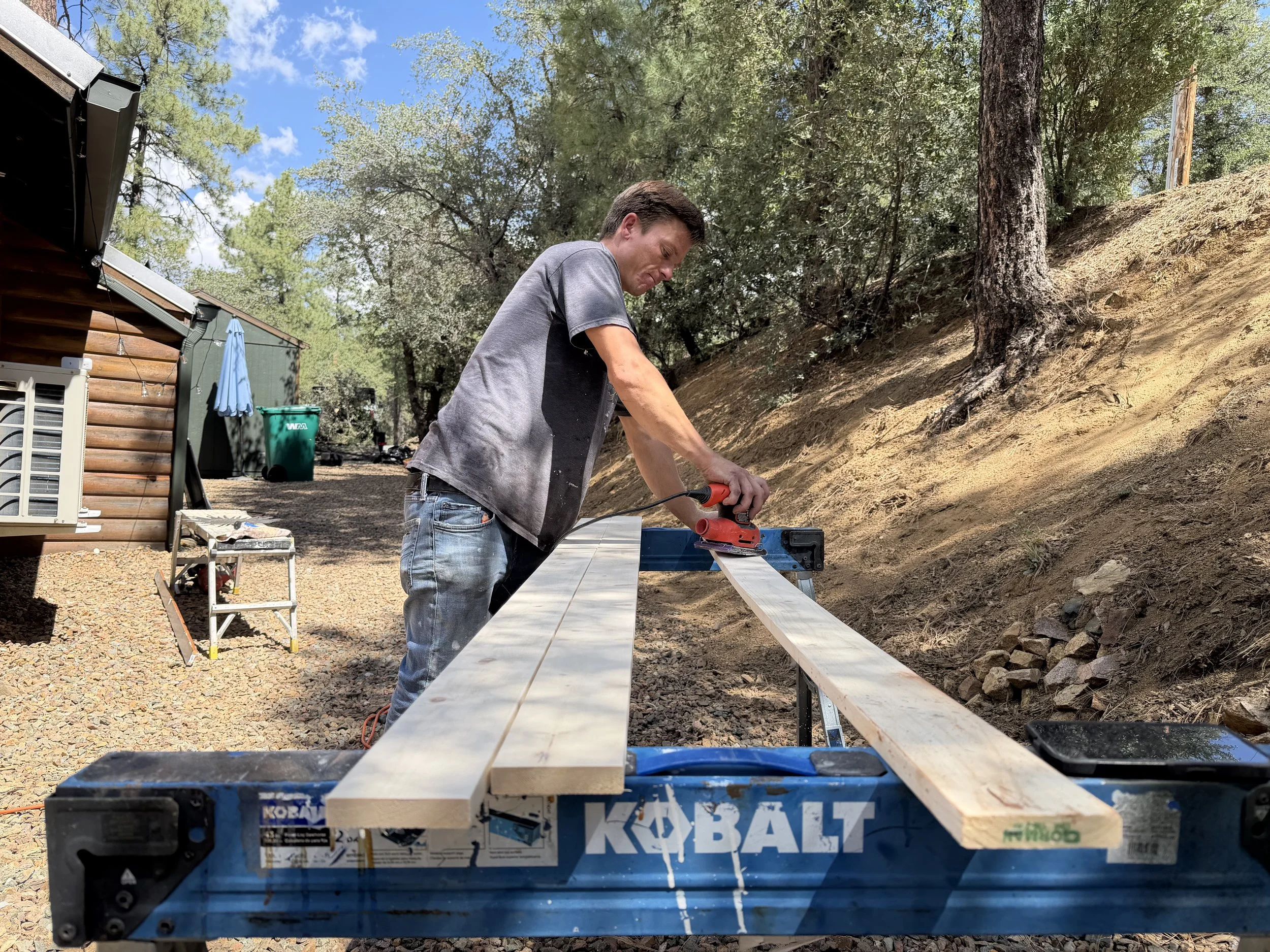 Sanding interior wood trim outdoors to prepare it for painting during a Prescott, Arizona renovation project.