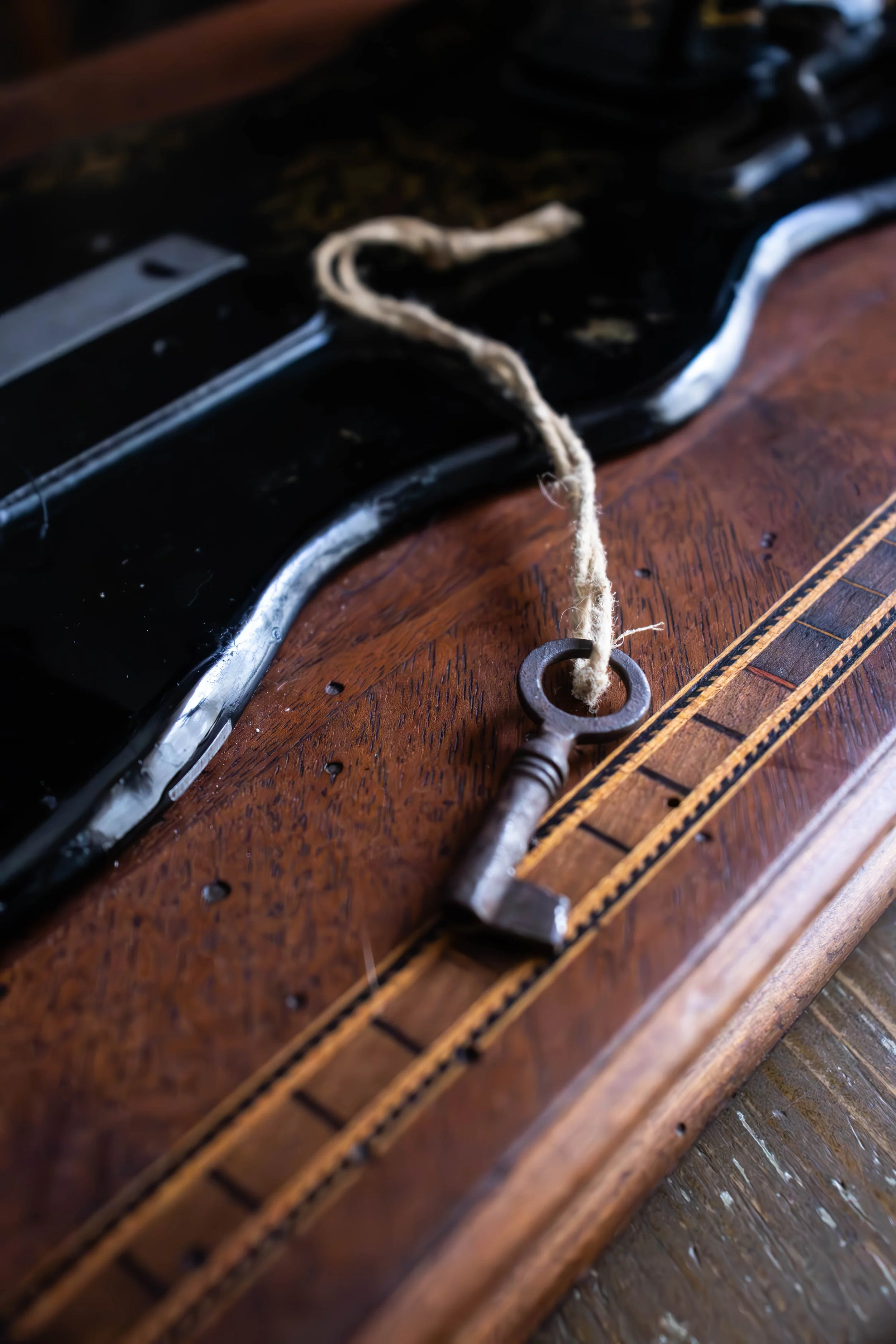 Une clé ancienne reliée à une corde, posée sur une table en bois, à côté d'un outil en bois avec une décoration en plastique.
