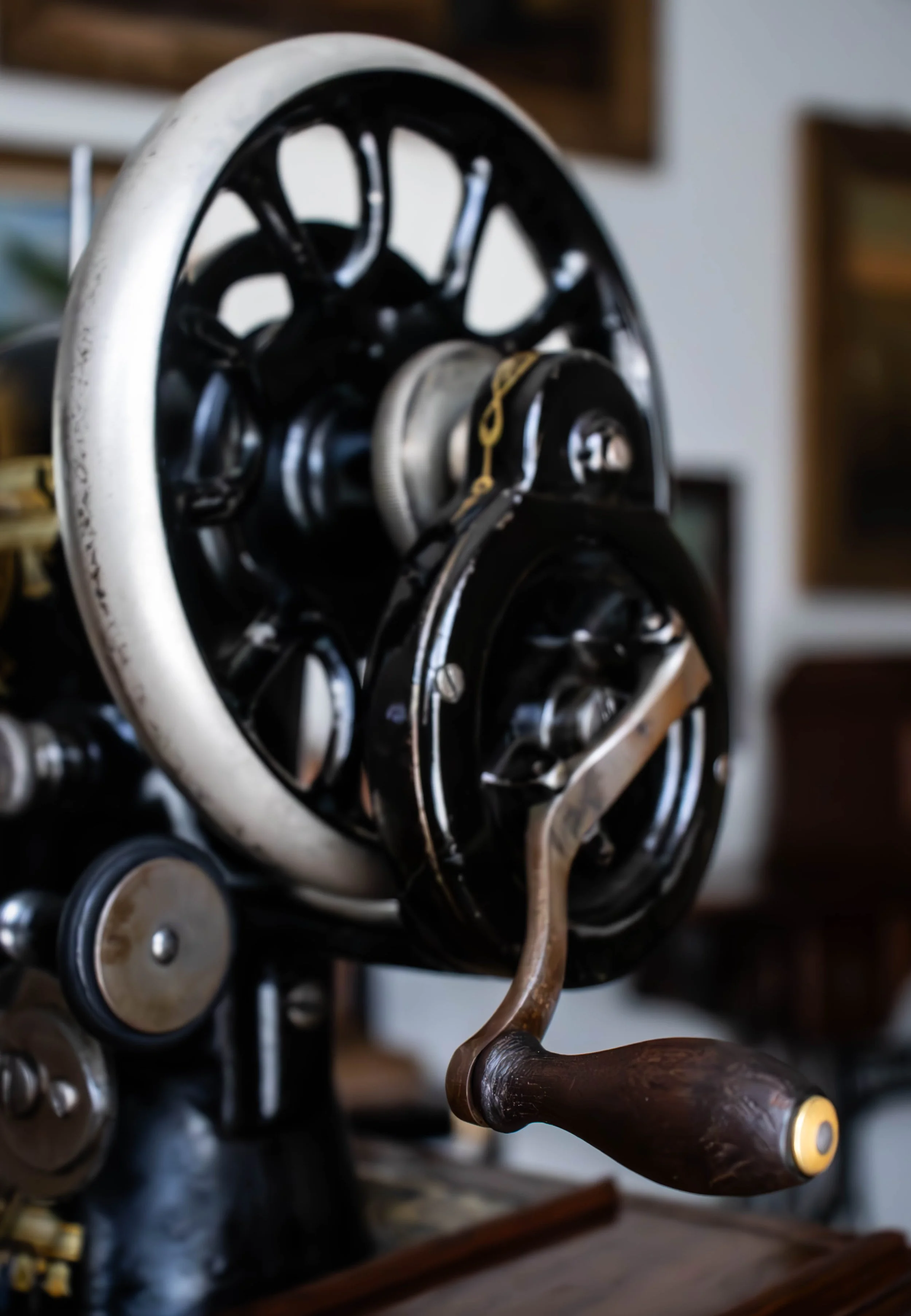 Une mirette vintage en métal avec un manche en bois, placée devant un ensemble d'expressions mécaniques noires et métalliques, probablement une machine ou un objet technique.