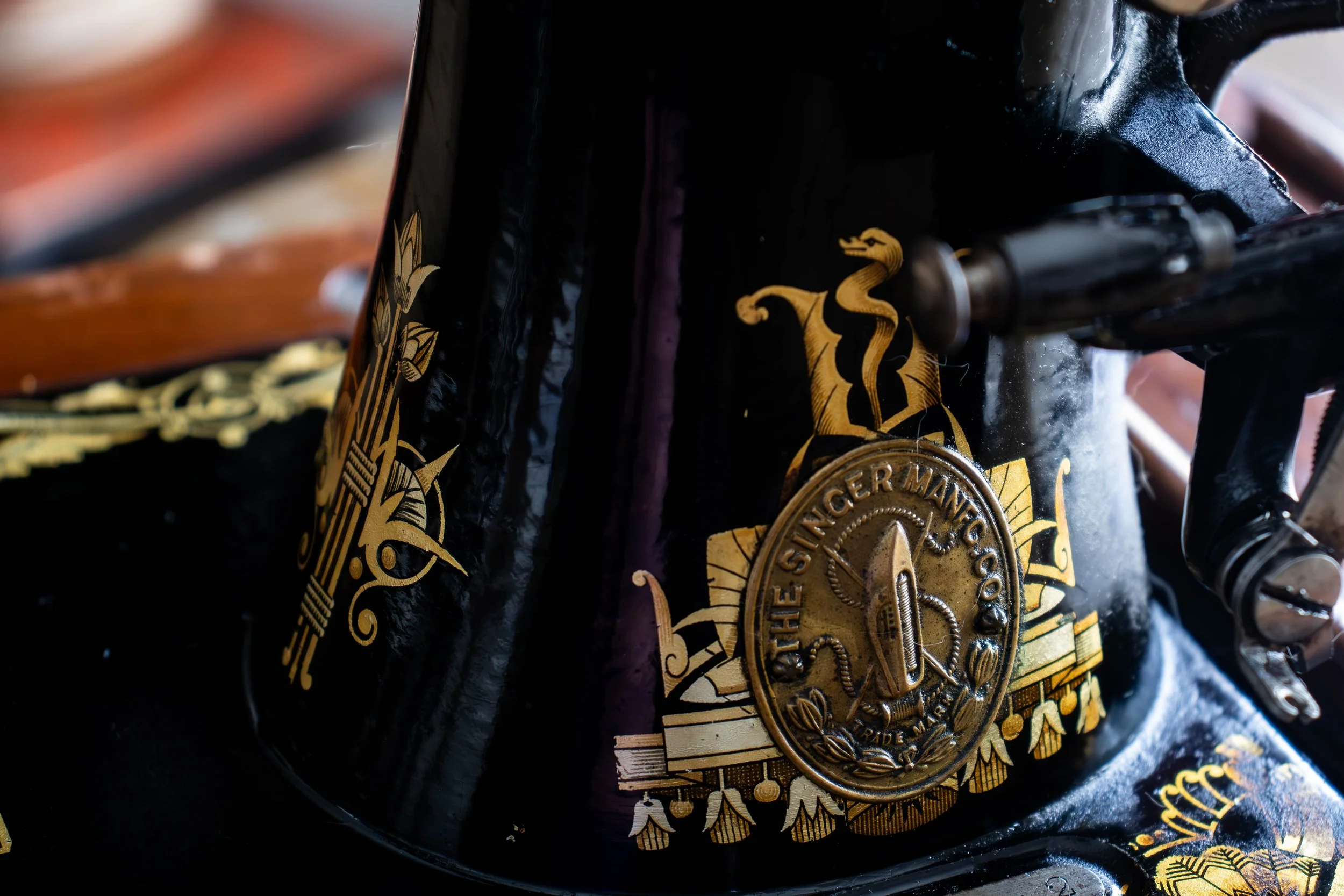 Détail d'une médaille dorée avec des inscriptions, fixée à une pièce de véhicule noir avec des motifs dorés.