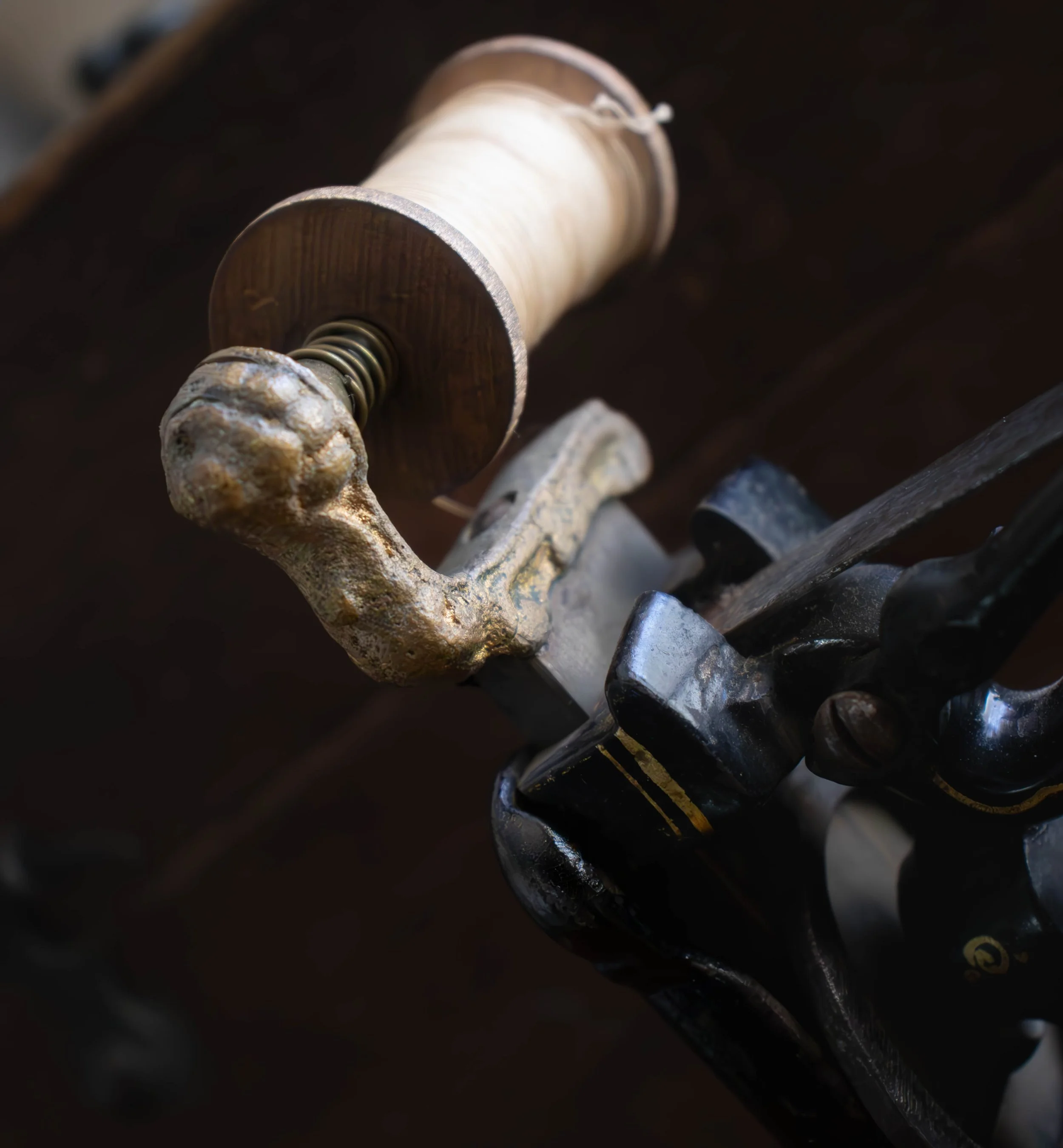 Une bobine de fil beige positionnée sur une machine de filature en métal.