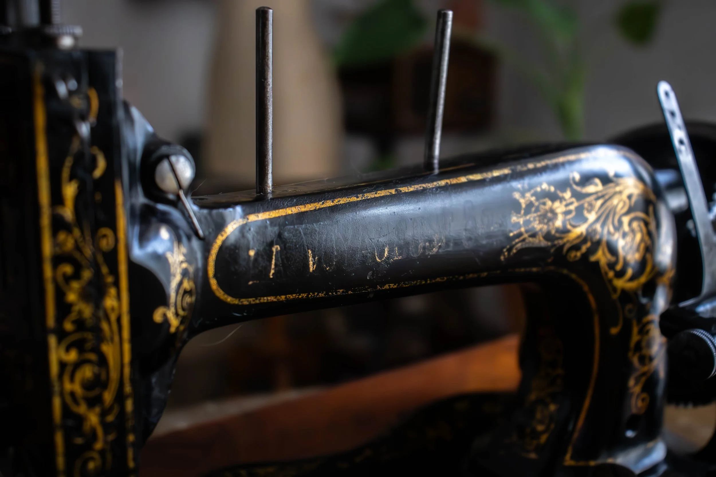 Une vieille machine à couture noire avec des ornements dorés et deux aiguilles apparentes.