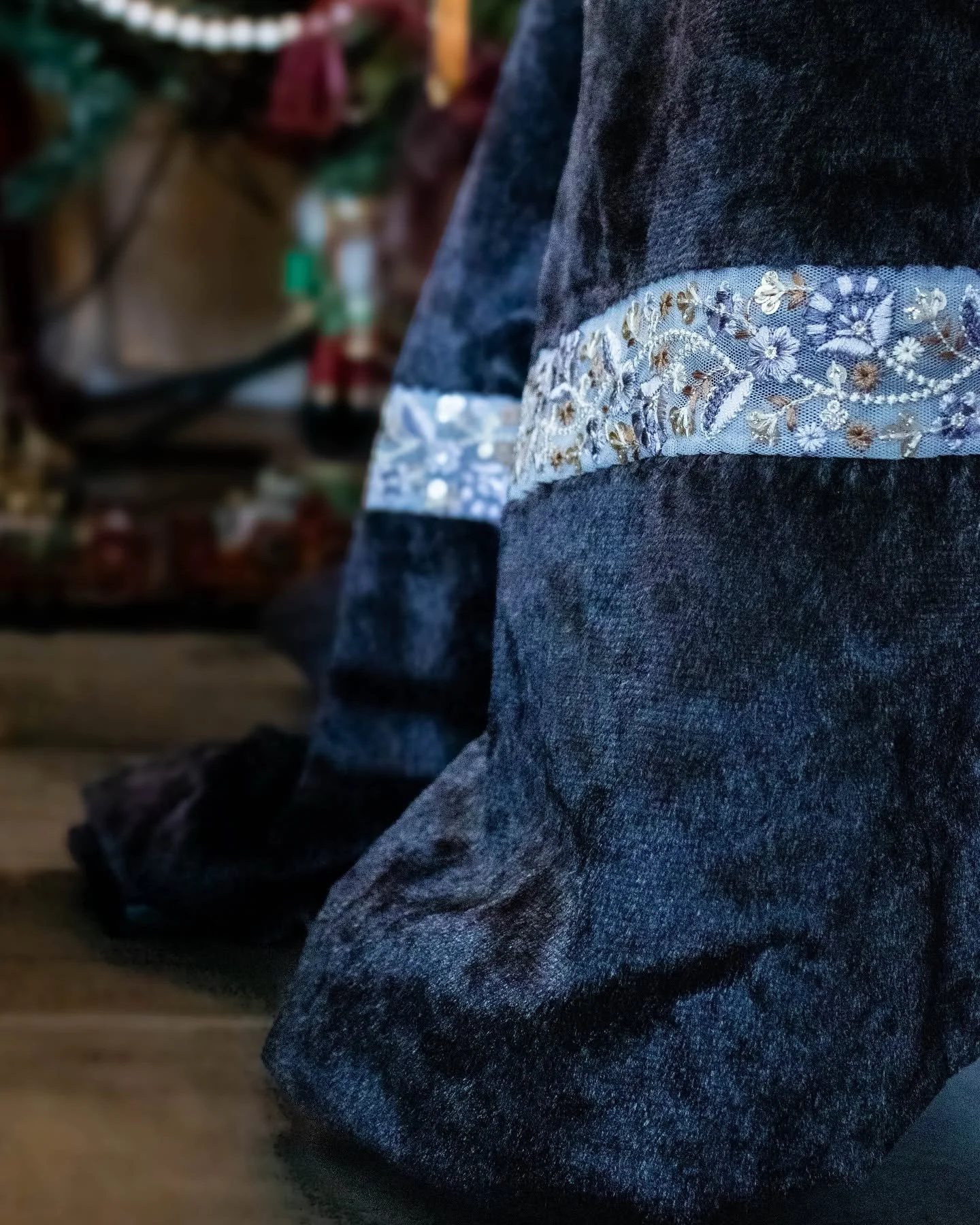 Une personne portant un pantalon en jean foncé avec une bande de dentelle ornée de fleurs sur la jambe