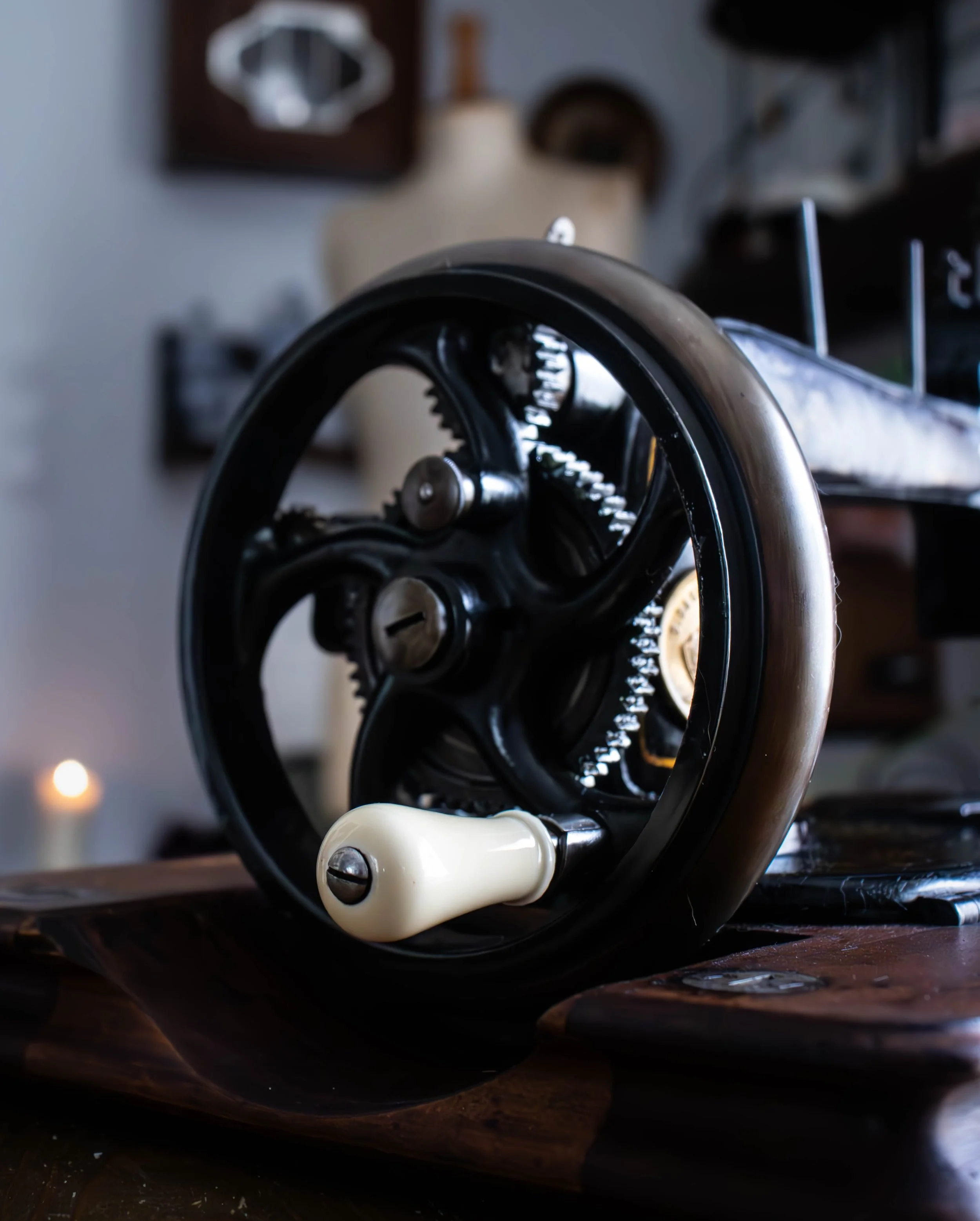 Une machine à écrire vintage noire avec une touche blanche est placée sur une surface en bois foncé. En arrière-plan, une lampe et des décorations murales sont visibles, floues.