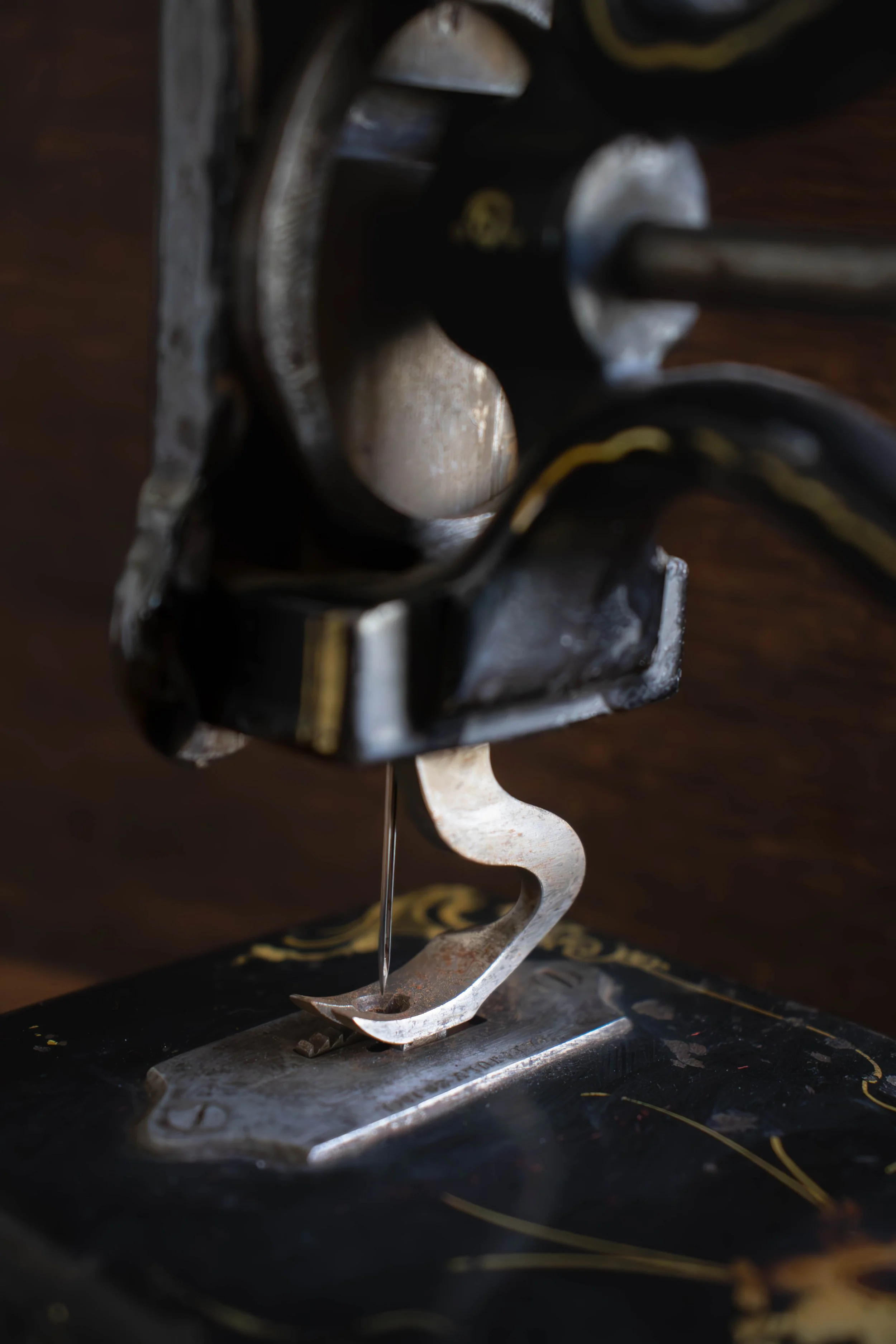 Une sculpture en métal représentant une forme humaine stylisée, avec une base et un éléments métalliques suspendus ou intégrés, posée sur une surface sombre.