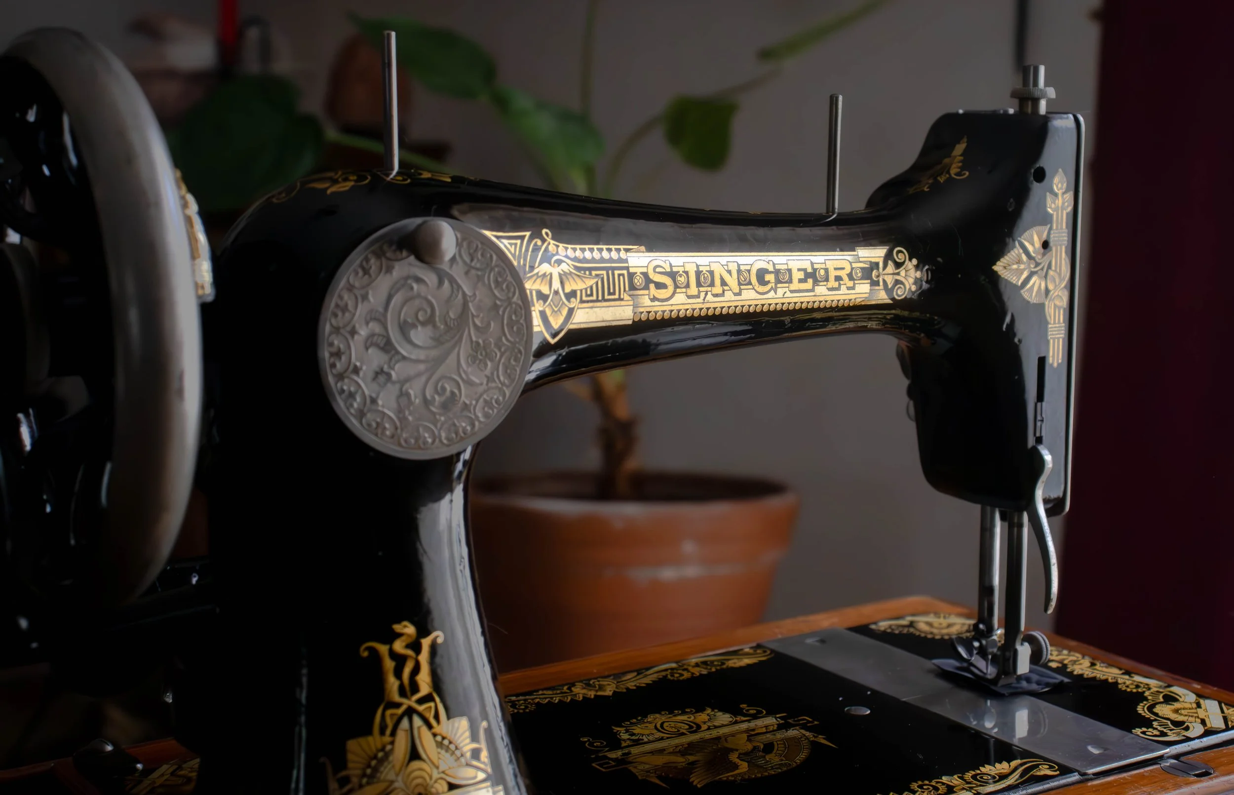 Ancienne machine à coudre noire avec des détails dorés et la marque Singer