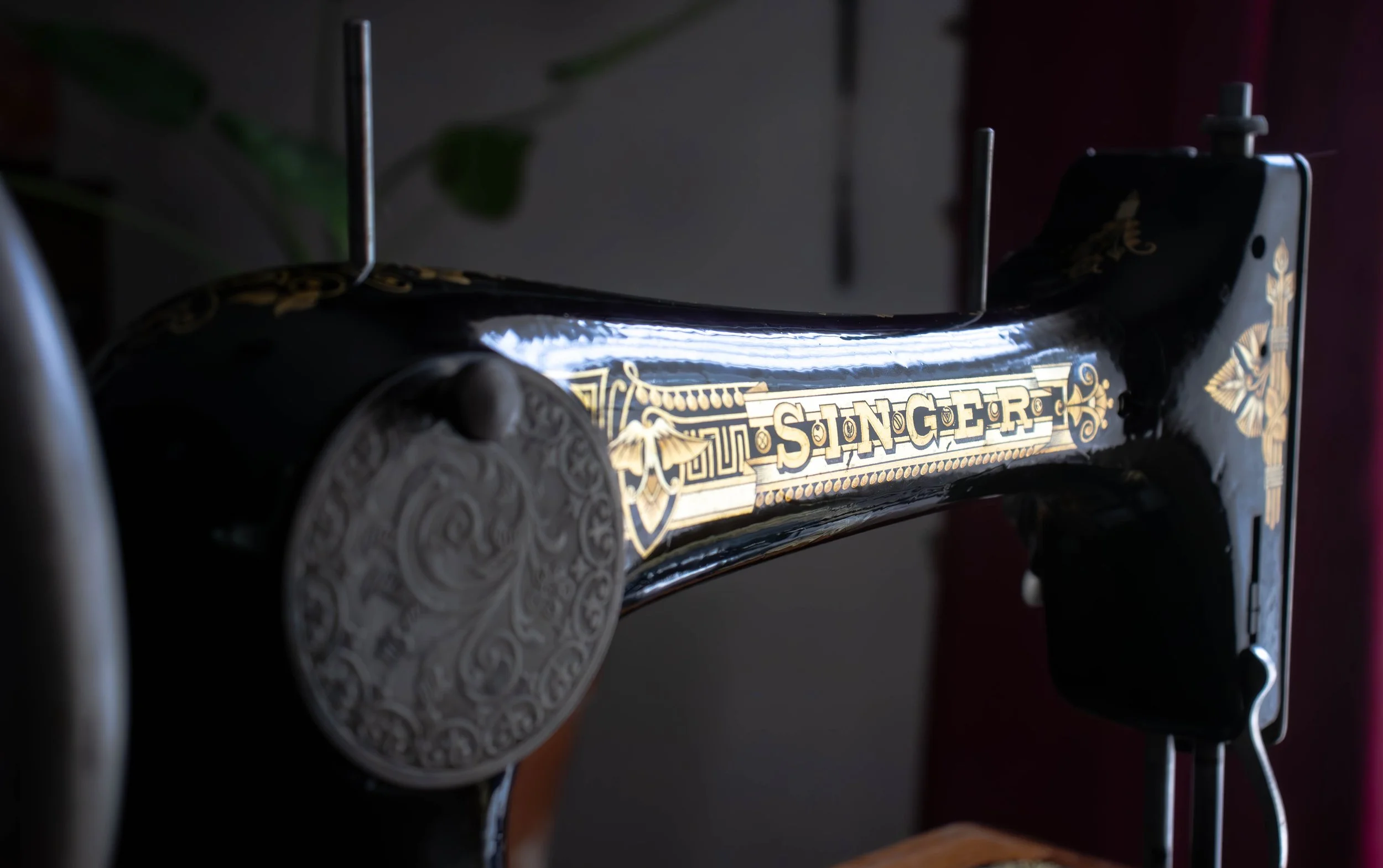 Une machine à coudre ancienne de marque Singer avec un design noir et or, partiellement visible dans une ambiance sombre.