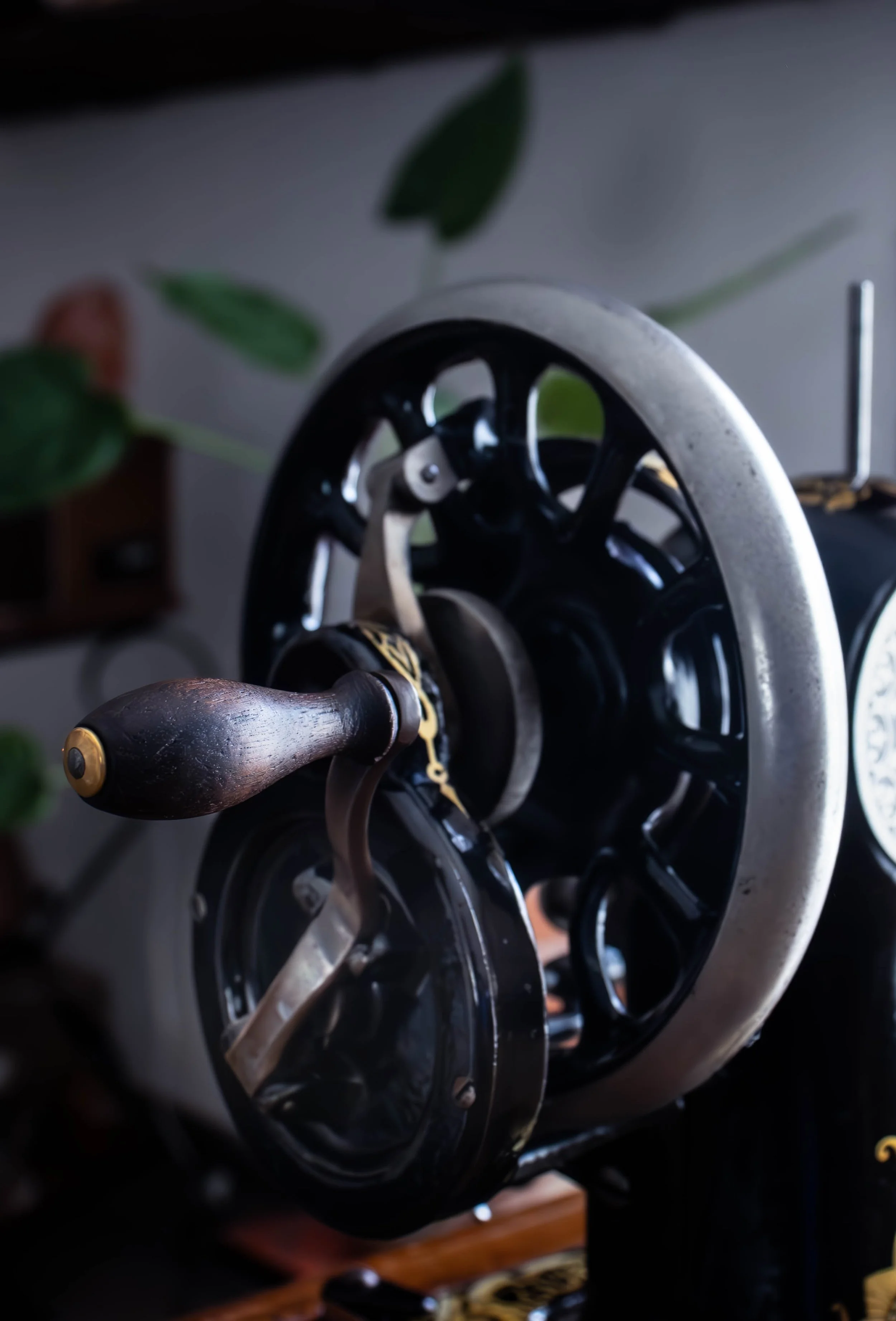 Photo en gros plan d'un moulin à vent en métal avec une pale en bois, positionné à l'intérieur, entouré de végétation verte.
