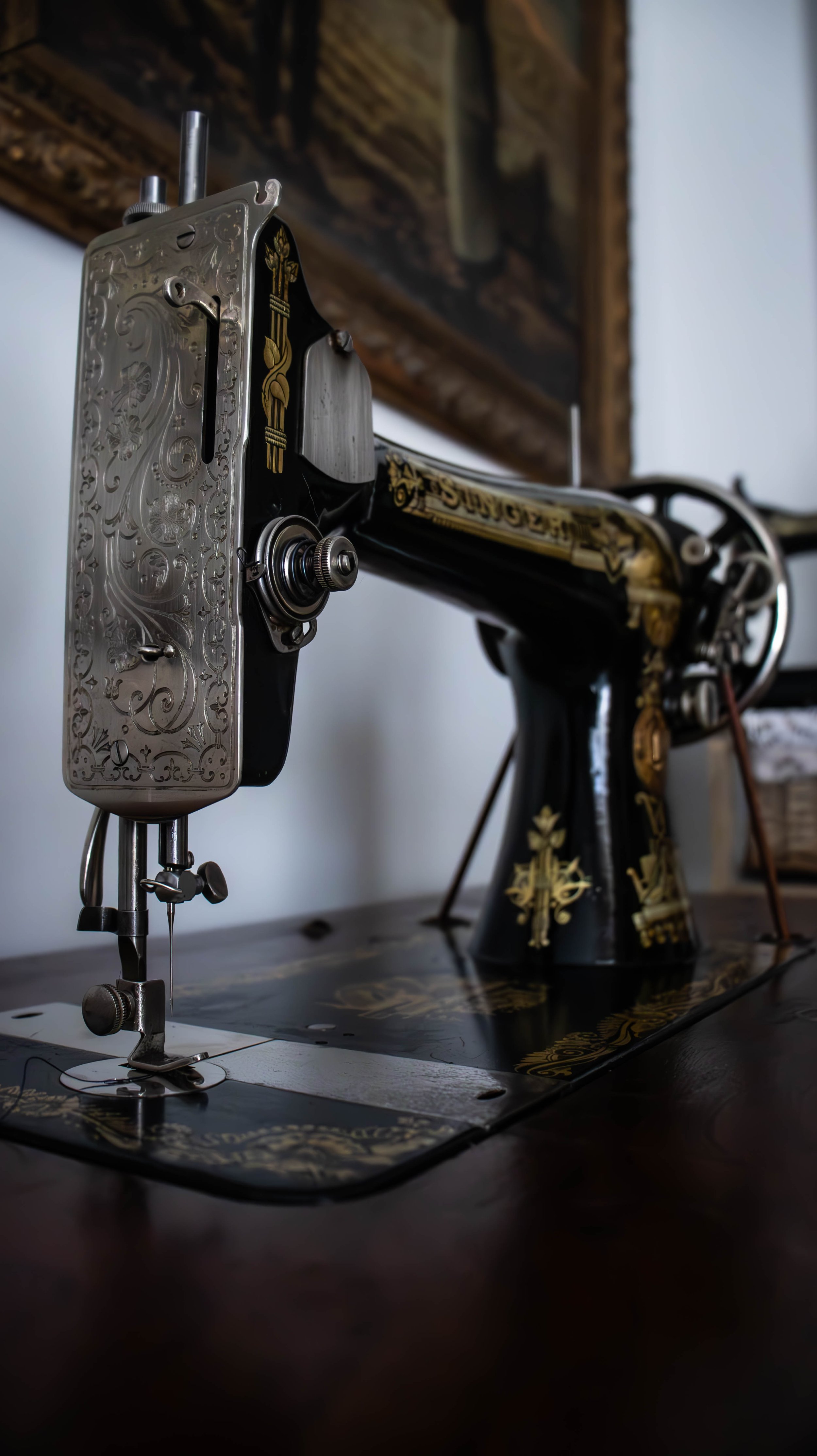 Une machine à coudre ancienne avec des détails dorés et noirs, placée sur une surface en bois.