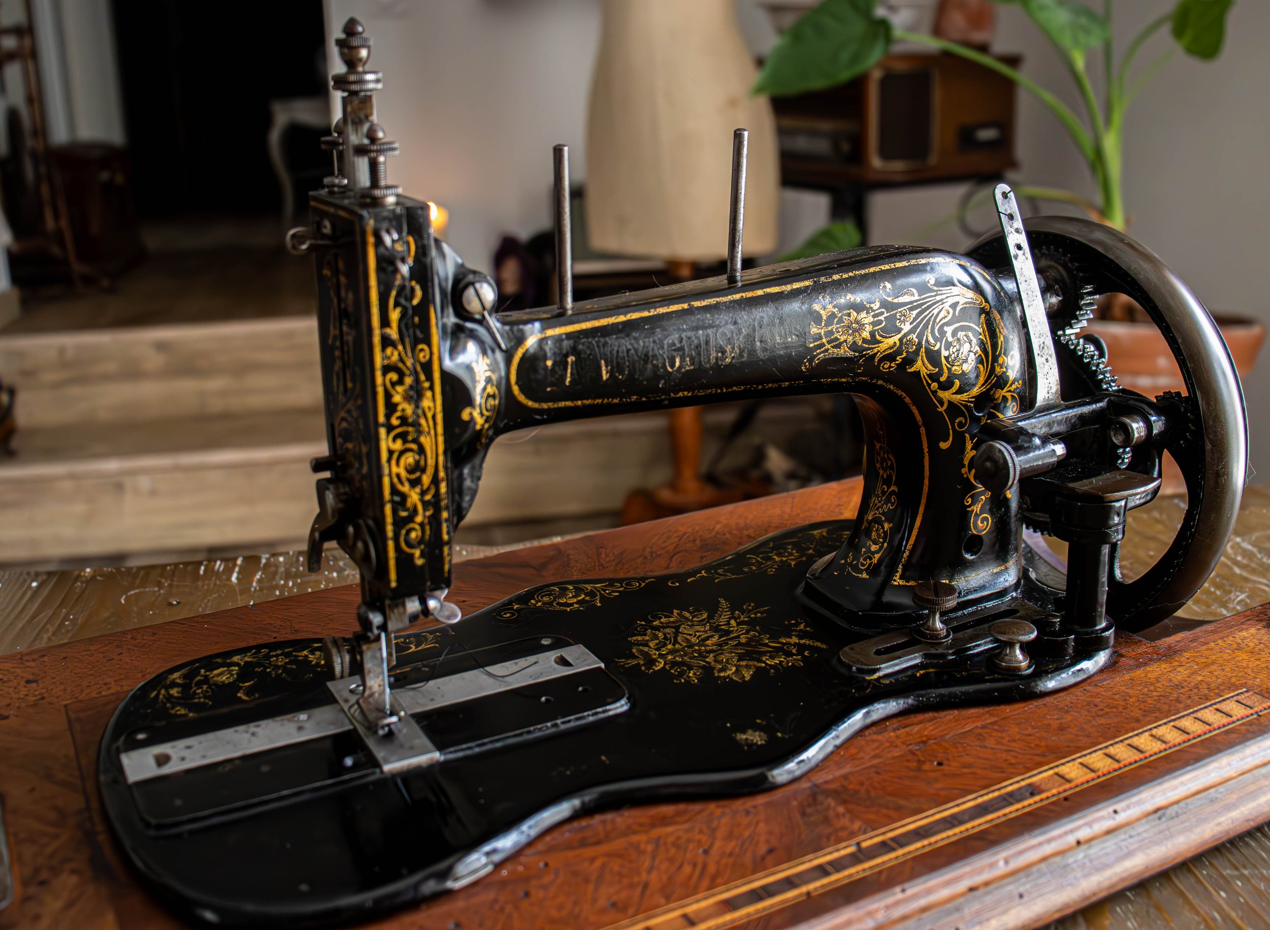 Une machine à coudre ancienne noire avec des décorations dorées, placée sur une table en bois.