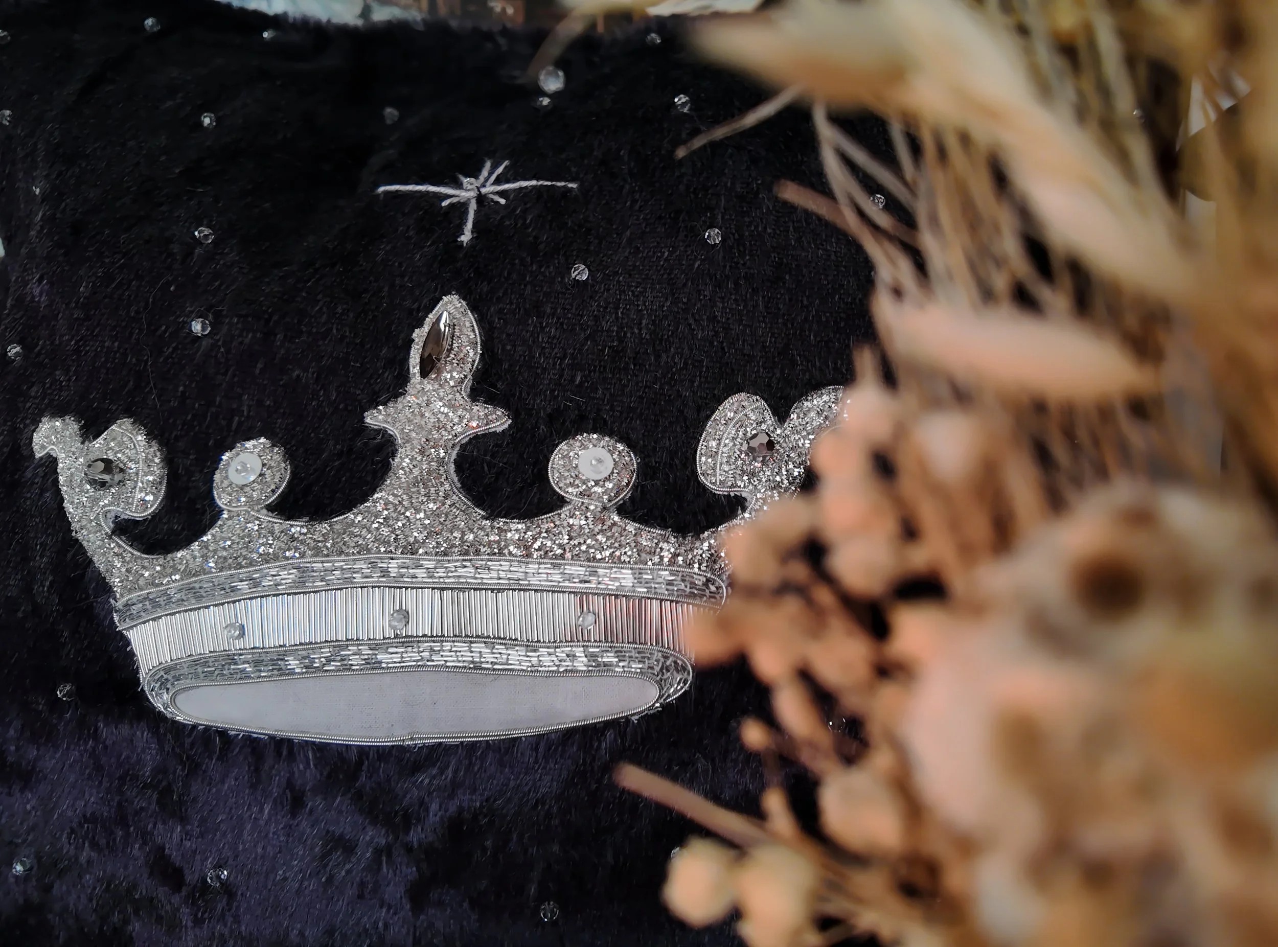 Une robe noire ornée de bijoux en forme de croix et de cercles, avec un décor de fausse fourrure dorée en arrière-plan.