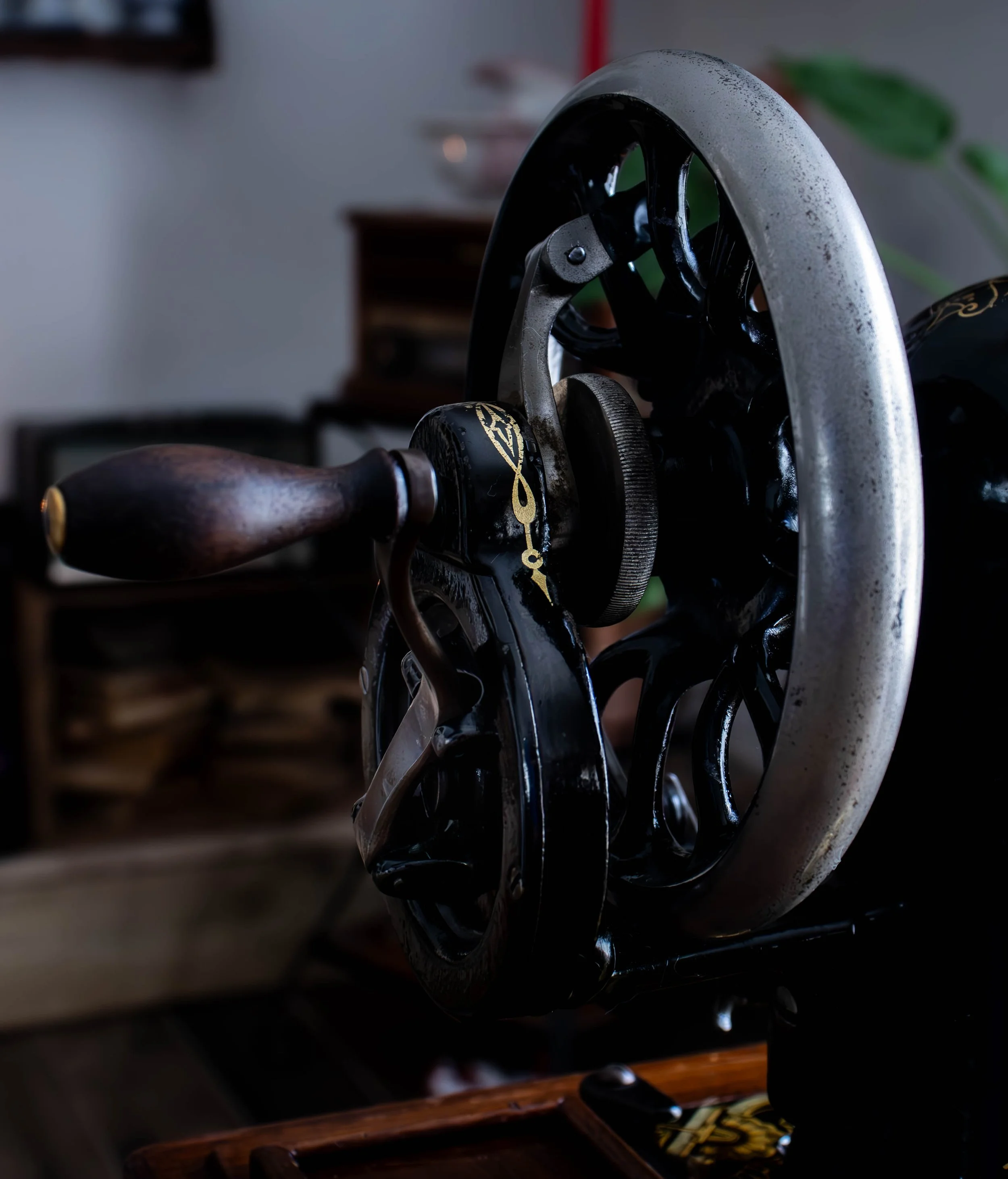 Un tourne-disque vintage avec une platine en métal argenté et une aiguille noire, posé sur une surface en bois, dans un décor intérieur sombre.