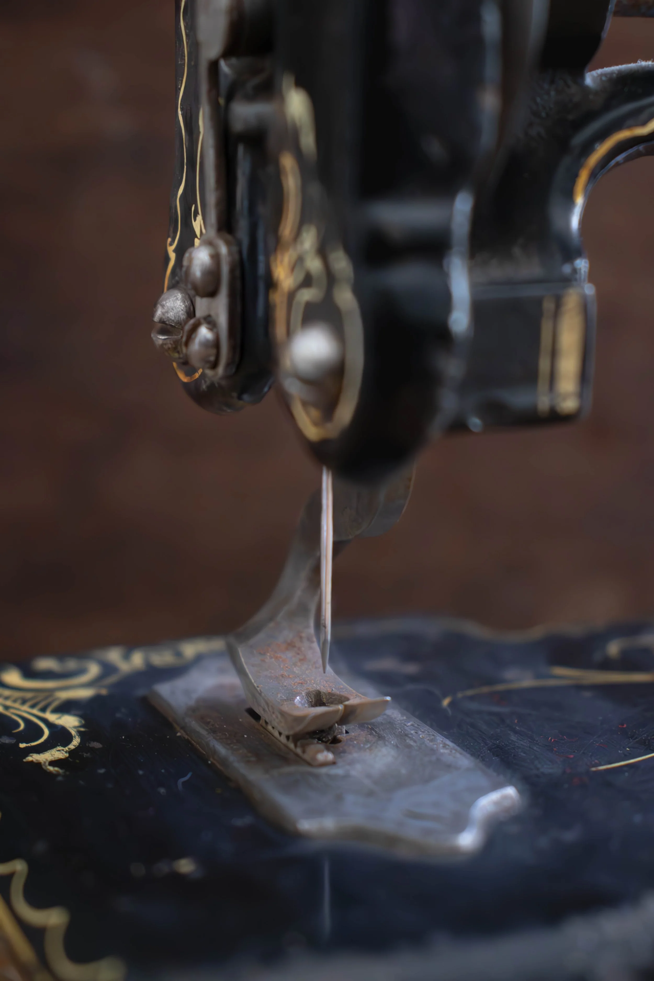Une machine à coudre ancienne avec une surface en métal et des détails dorés, se trouvant sur une surface sombre