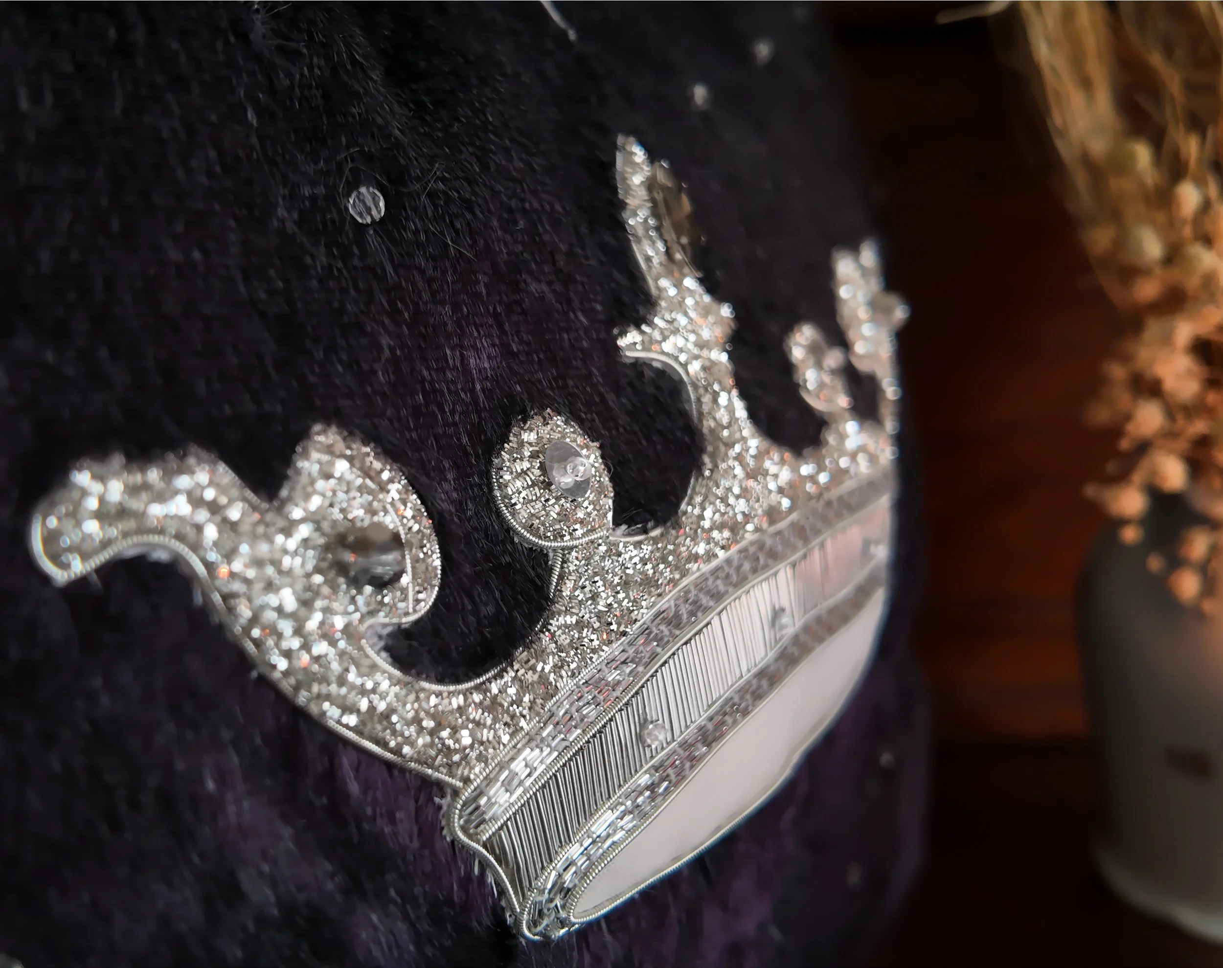 Collier en argent avec de nombreuses pierres brillantes, posé sur un fond noir en peluche.