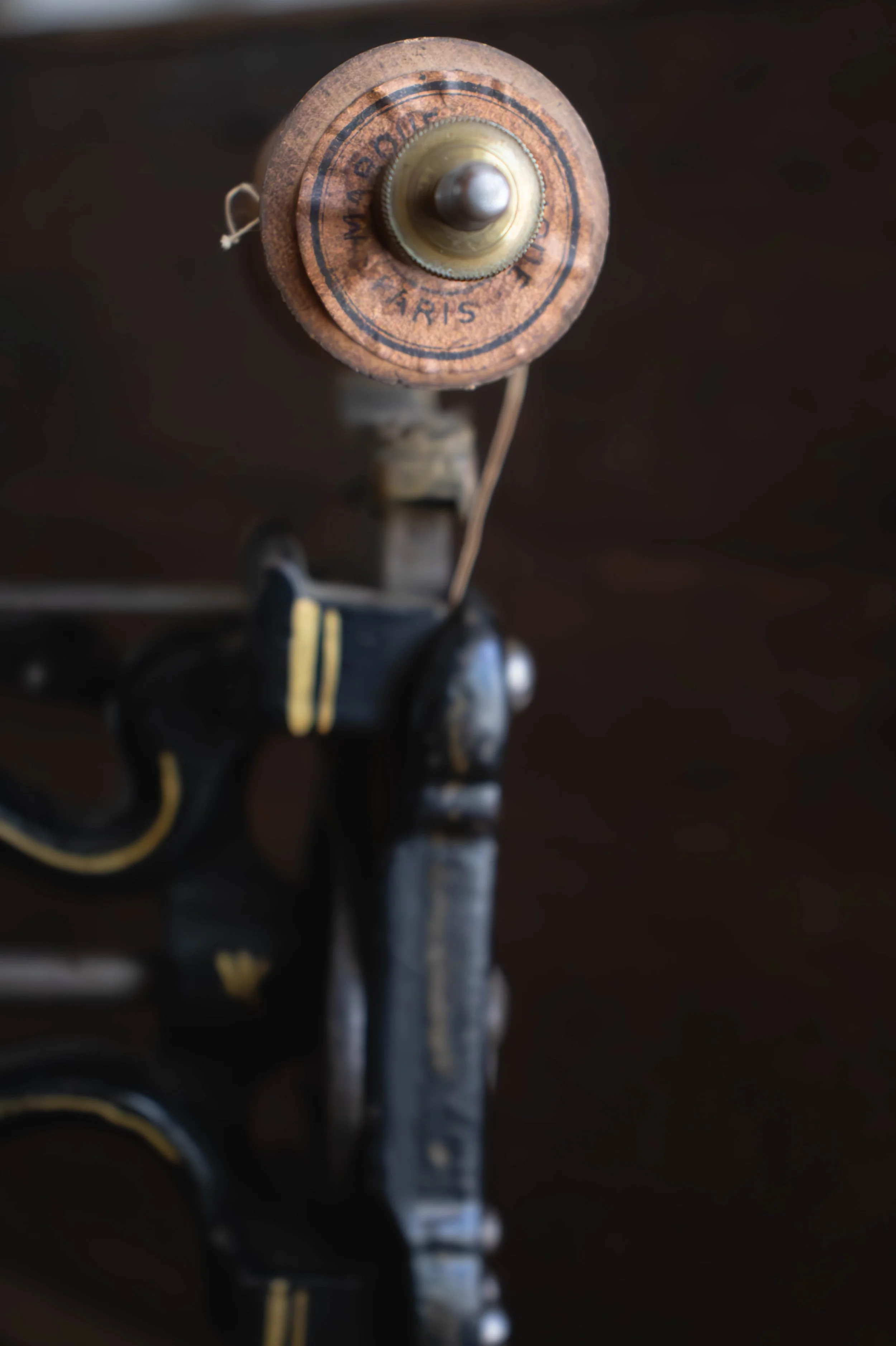 Vue en plongée d'un objet vintage, possiblement une lampe ou un boîtier avec un bouton ou une tête ronde, portant une inscription en français, sur un fond sombre.