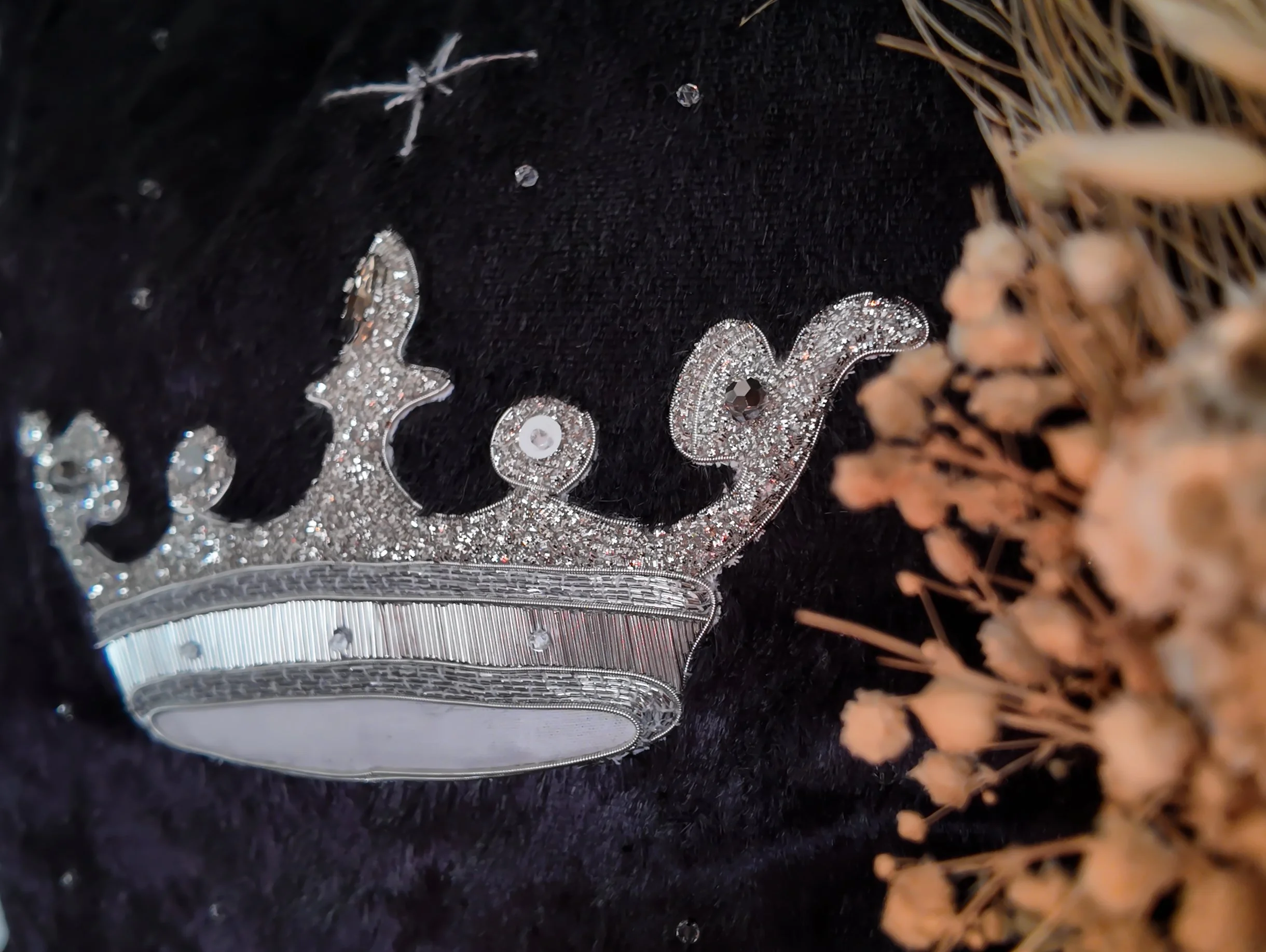 Un détail de bijoux en argent ou en diamants avec des décorations brillantes, entouré de matériaux naturels puisé de bois ou de paille.