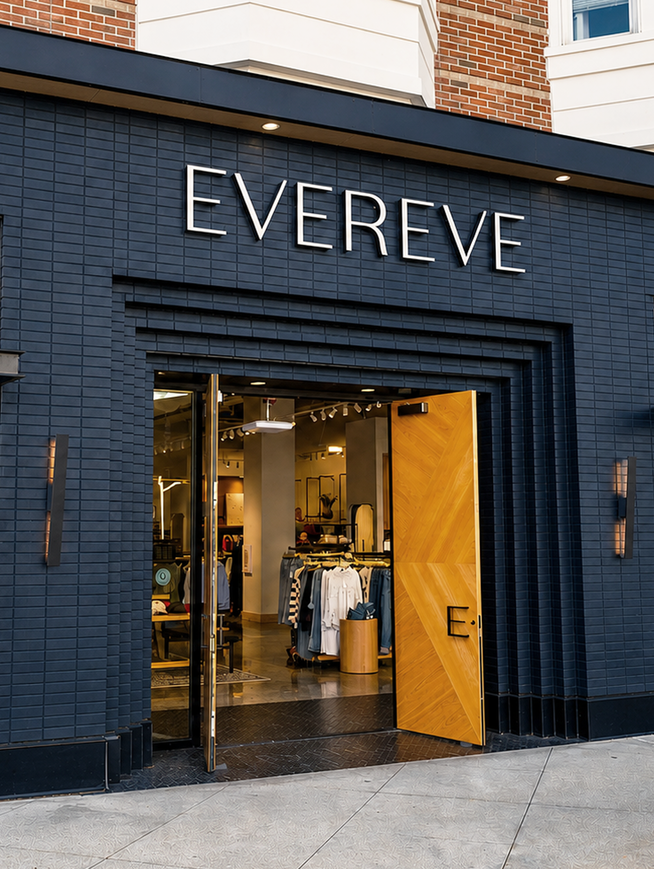 Storefront with black brick facade and a large sign reading 'EVER EVE' above the entrance, which features a wooden double door open to reveal clothing inside.