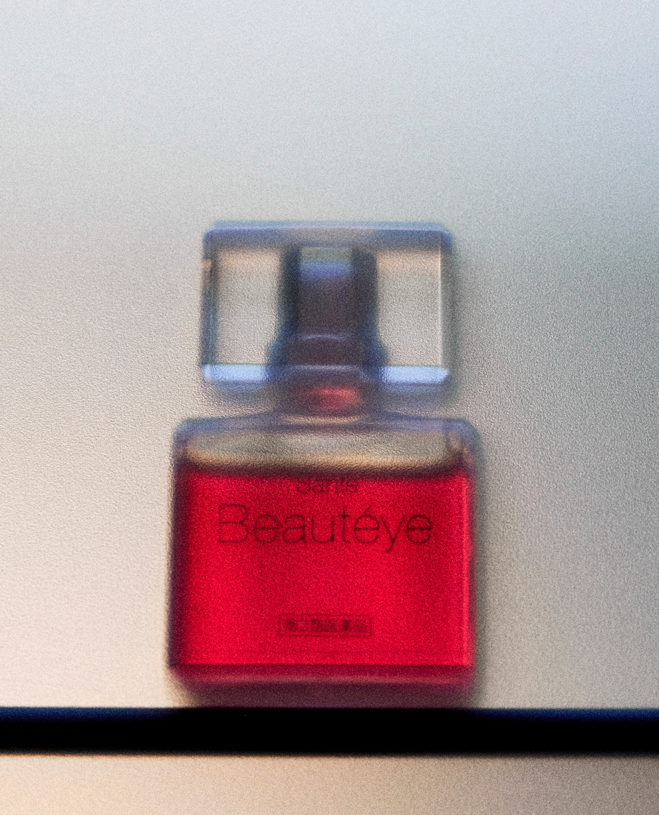Close-up of a perfume bottle labeled 'Beauteve' with red liquid inside.
