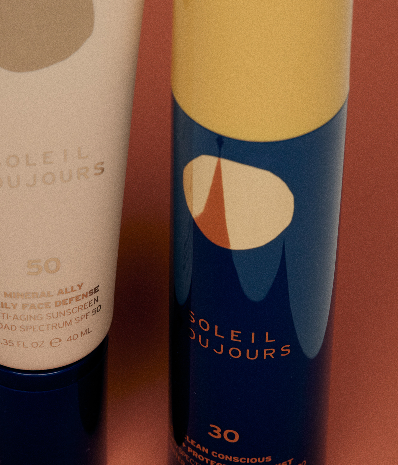 Close-up of a skincare product tube from Soleil Toujours with abstract colorful design and orange text.