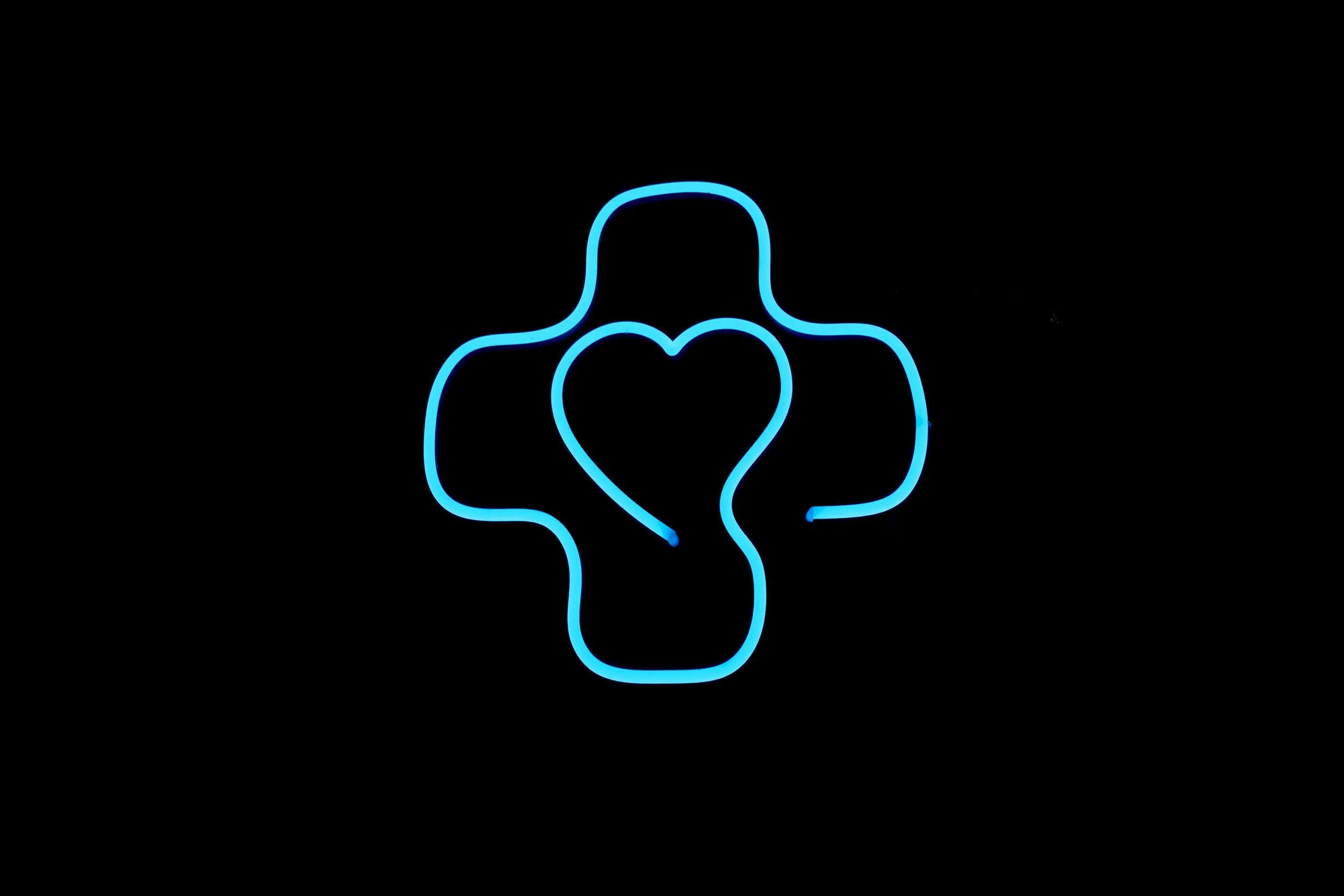 Neon sign of a stylized blue heart with a finger pointing up, set against a black background.