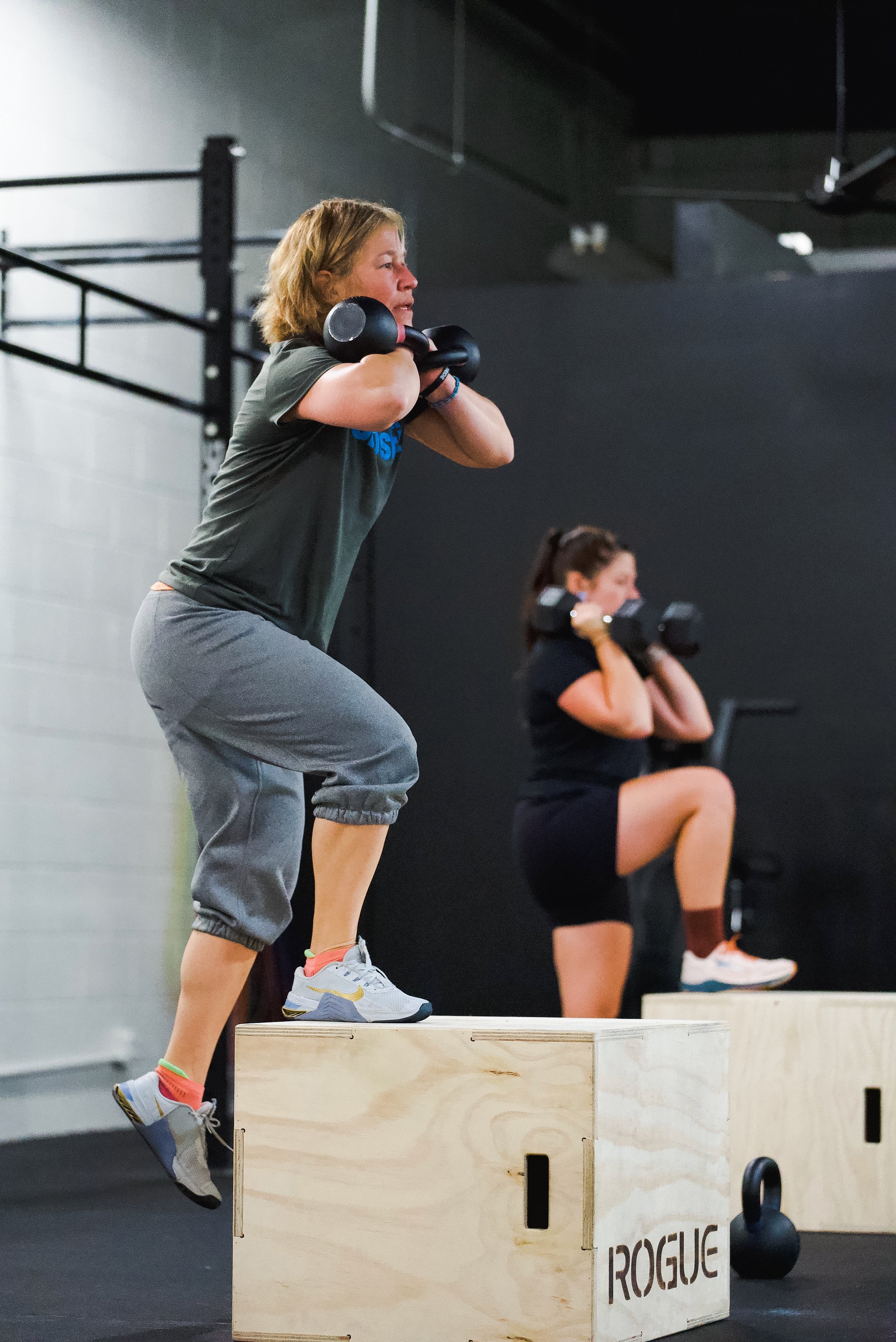 Override North strength training class in Avon, CT with women performing dumbbell step-ups during a coached workout.