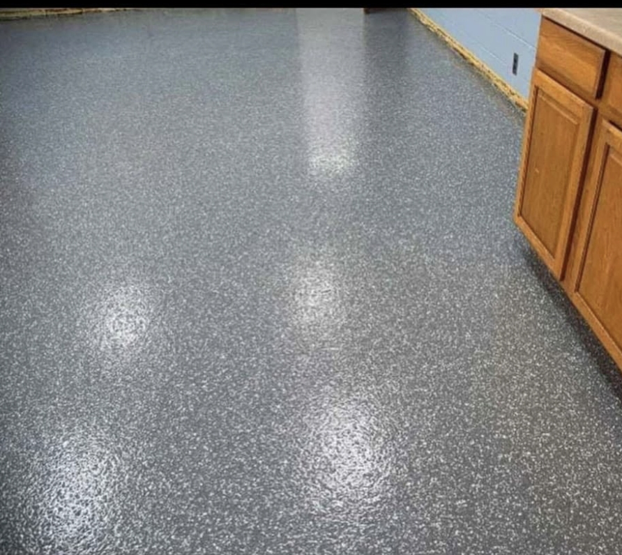 Polished blue-speckled epoxy flooring in a kitchen with wooden cabinets and a light blue wall.