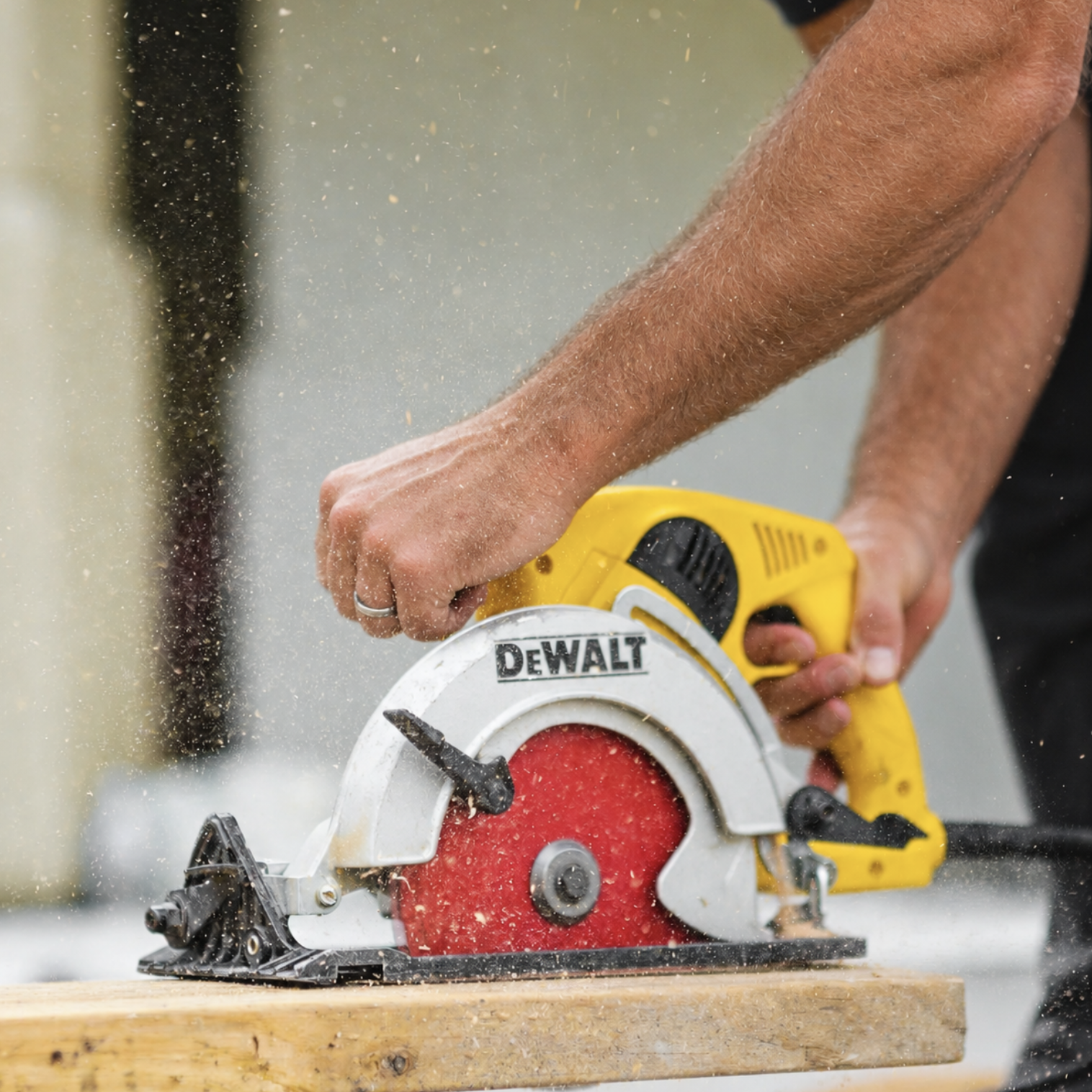A person using a yellow Dewalt circular saw to cut wood, with sawdust flying around.