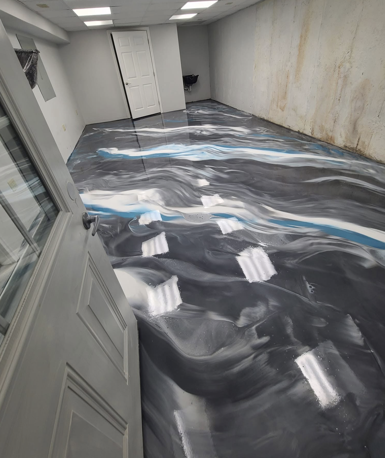 Epoxy-floor with swirling black, gray, white, and blue patterns.