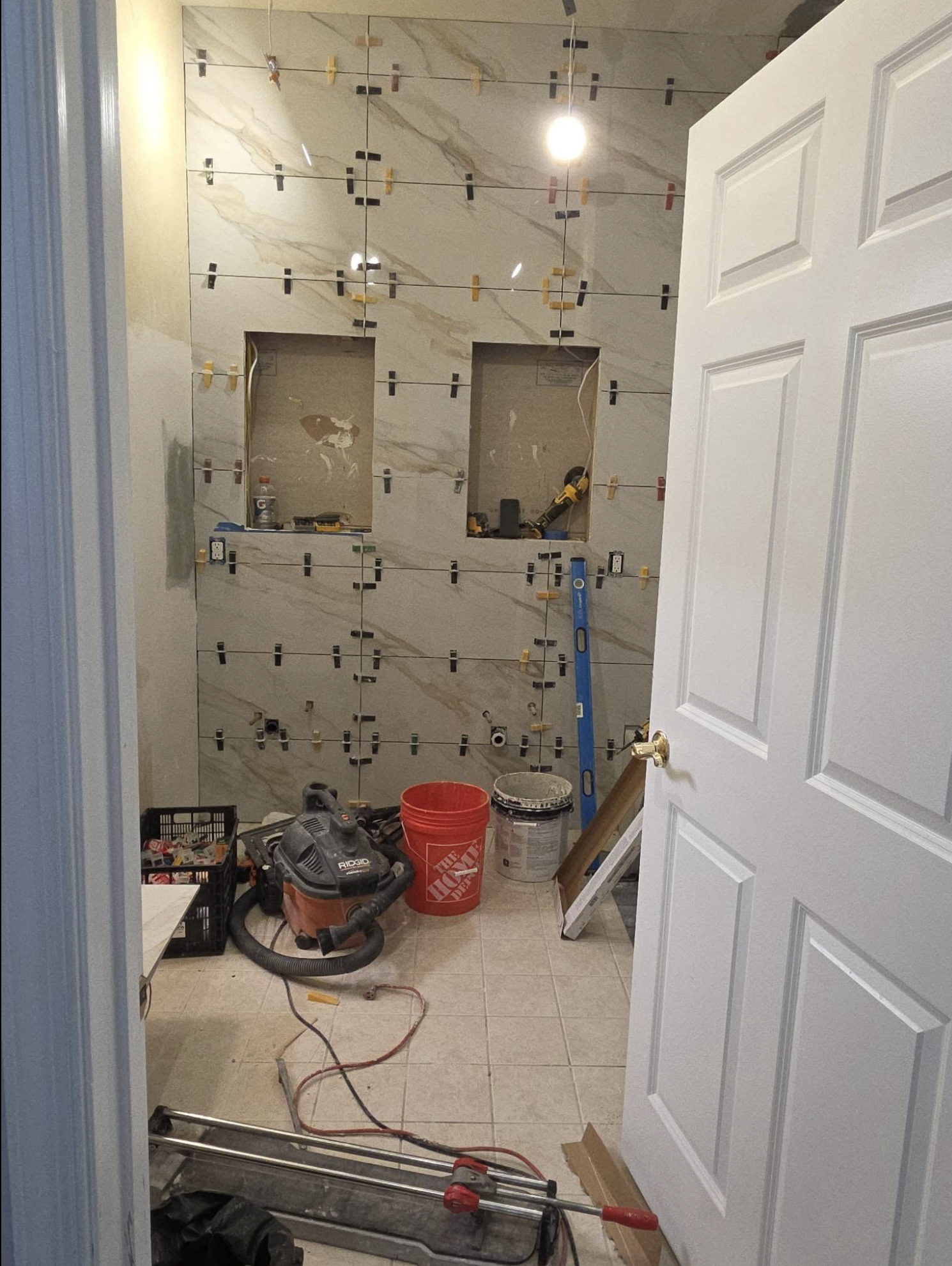 Bathroom under renovation with tools, construction materials, and tiled walls. 
