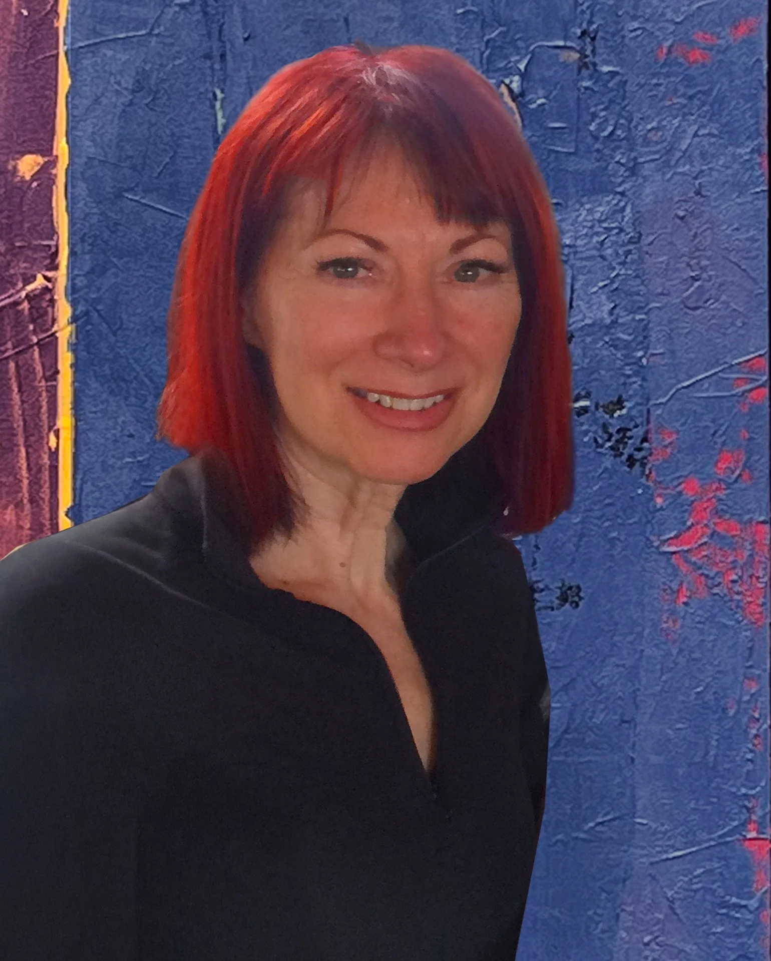 A woman with red hair wearing a black top, smiling, standing in front of a blue textured wall with pink and black designs.