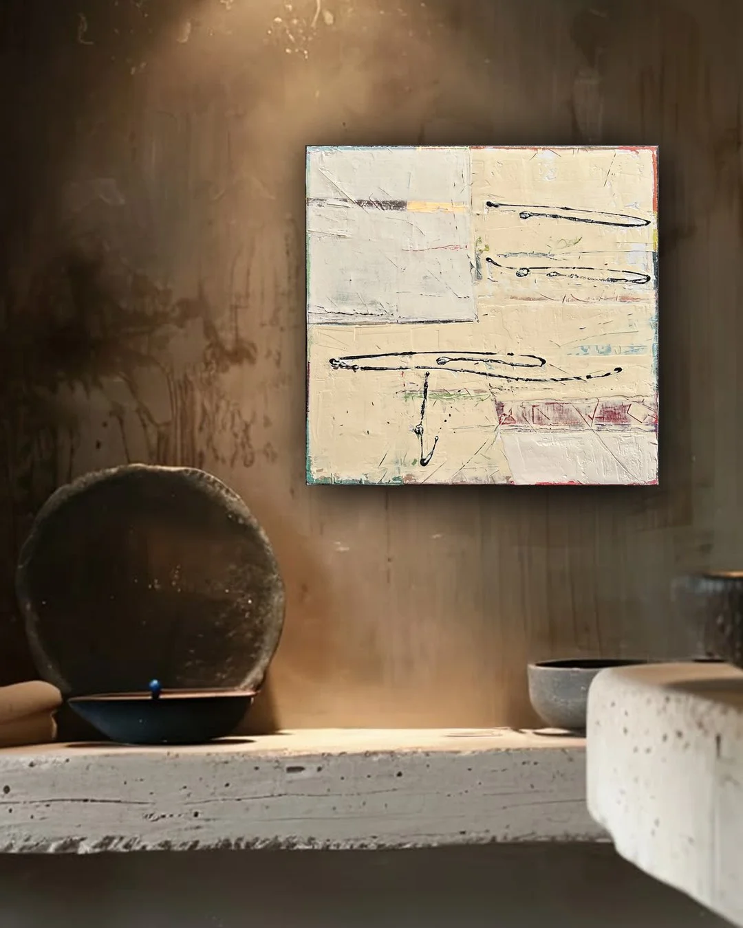 A wooden shelf with pottery bowls and a white textured painting with abstract black lines on a wooden wall.