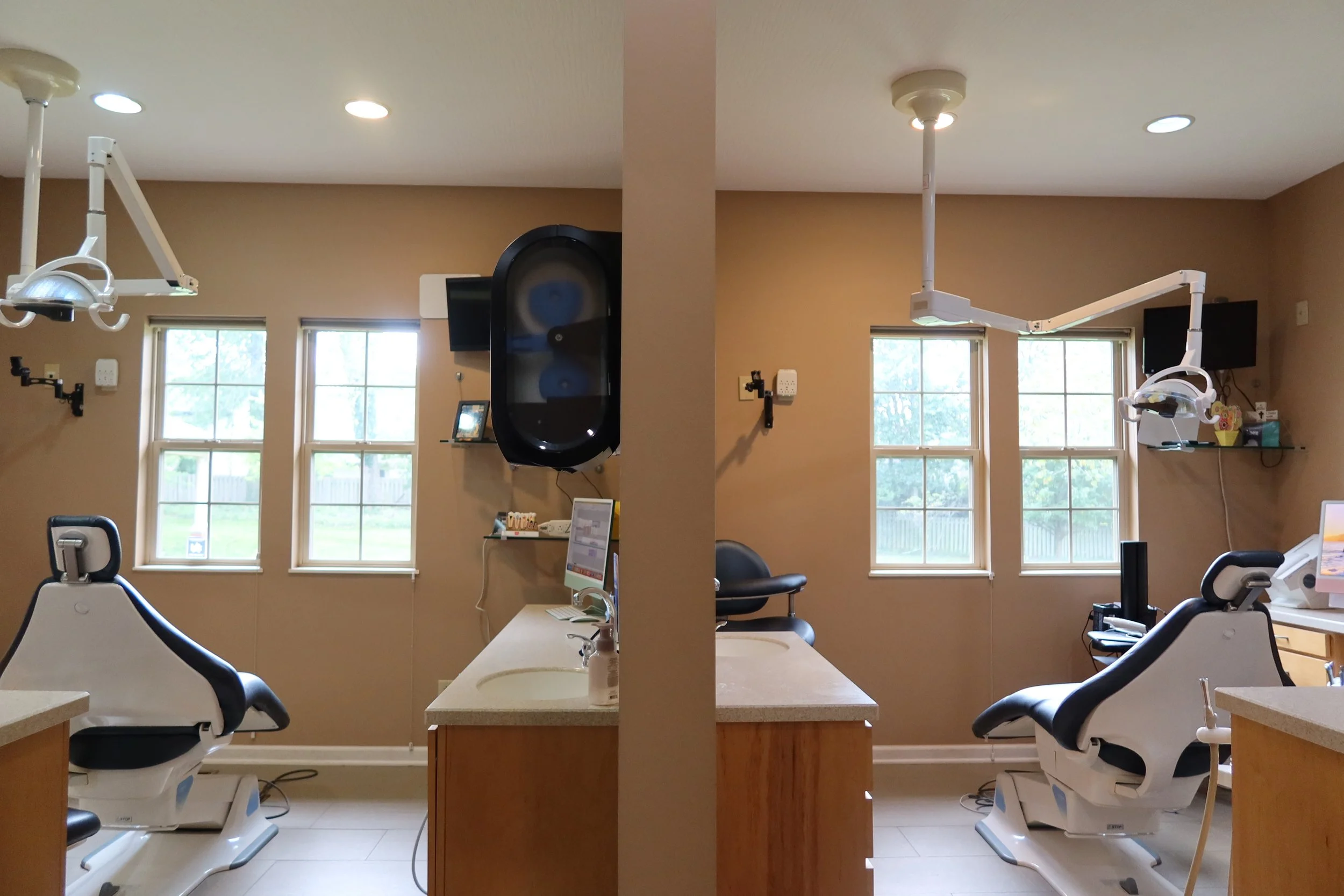 dental office in daylight, showing dental chairs, overhead lights, windows, and medical equipment.