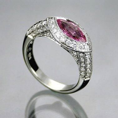 Marquise-shaped pink center stone surrounded by clear stones on a split silver-tone band.