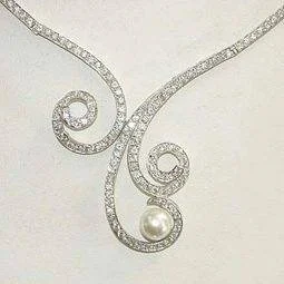 Silver-tone necklace with clear-stone scrolls and a cream-colored round drop.