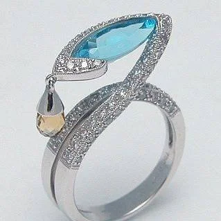 Sculptural bypass ring with a marquise-shaped blue stone, clear accents and a gold-tone teardrop detail.