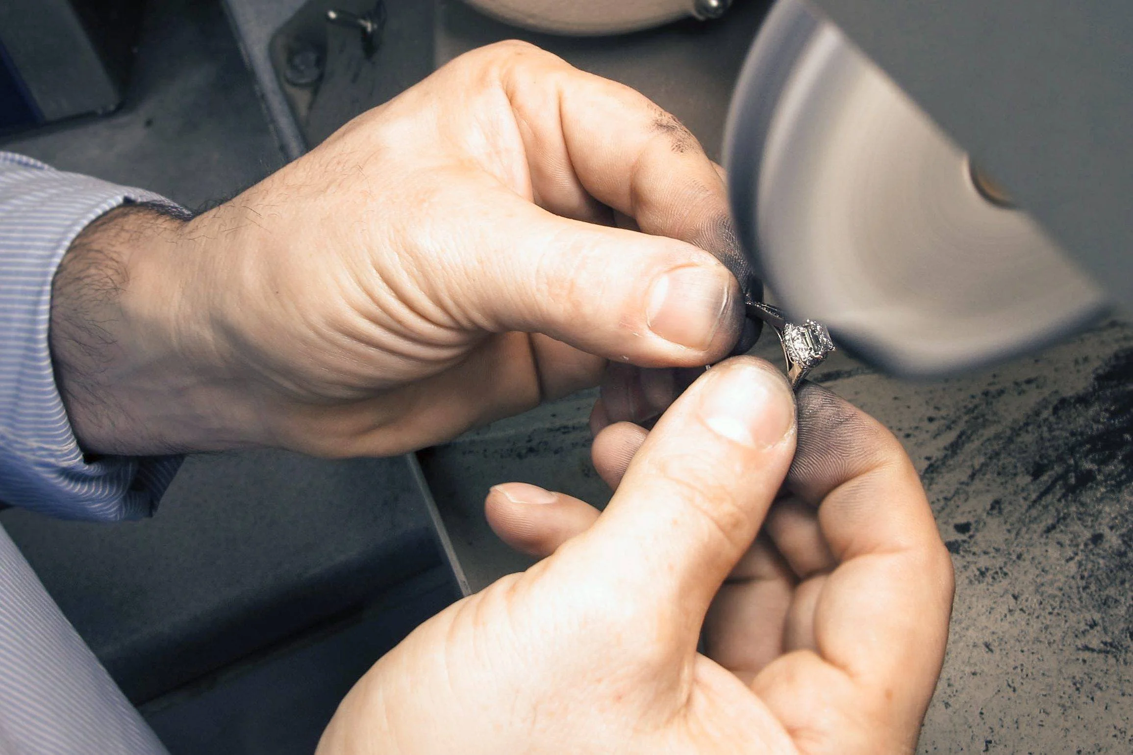 Close-up of Serjeo holding a clear-stone ring against a spinning polishing wheel.
