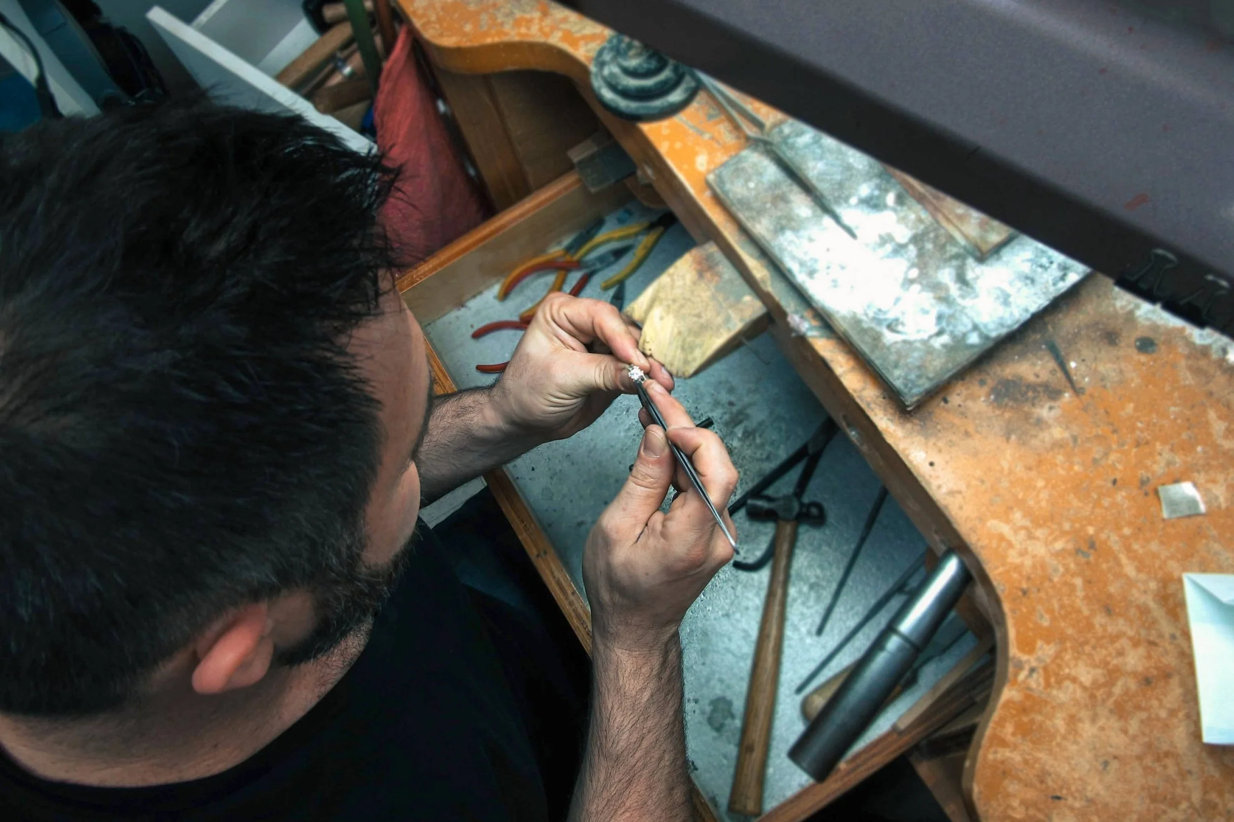 Serjeo using a hand tool on a ring at his jeweler’s bench.