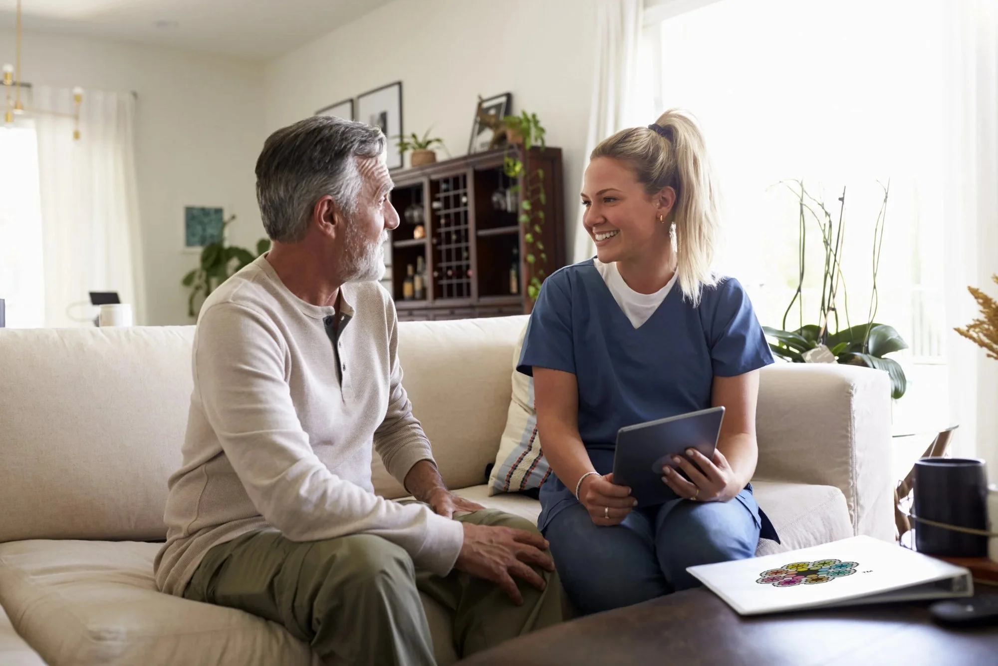 Home infusion nurse talking with a patient in his living room