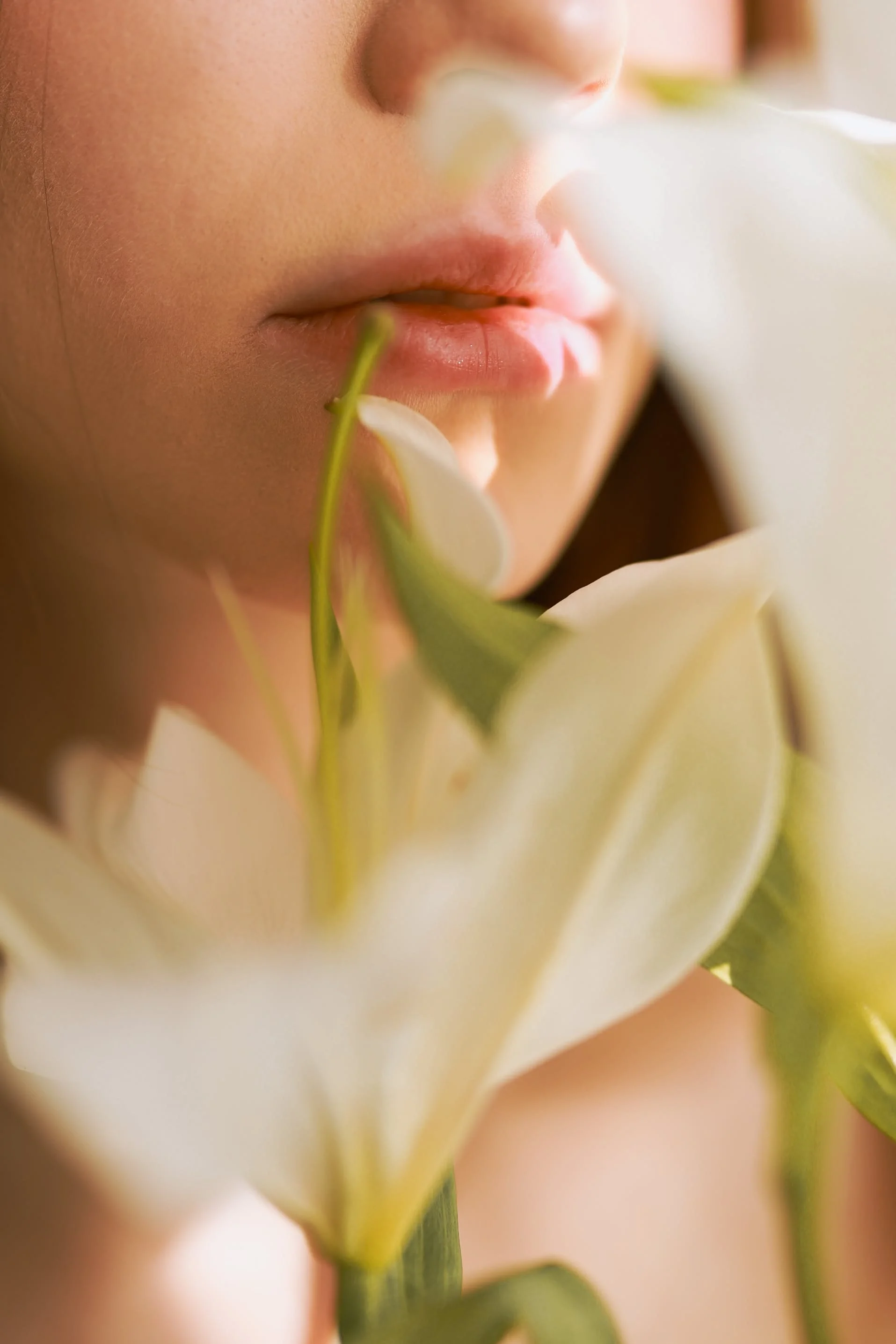 Close-up of a woman's lips with a white flower near her face.