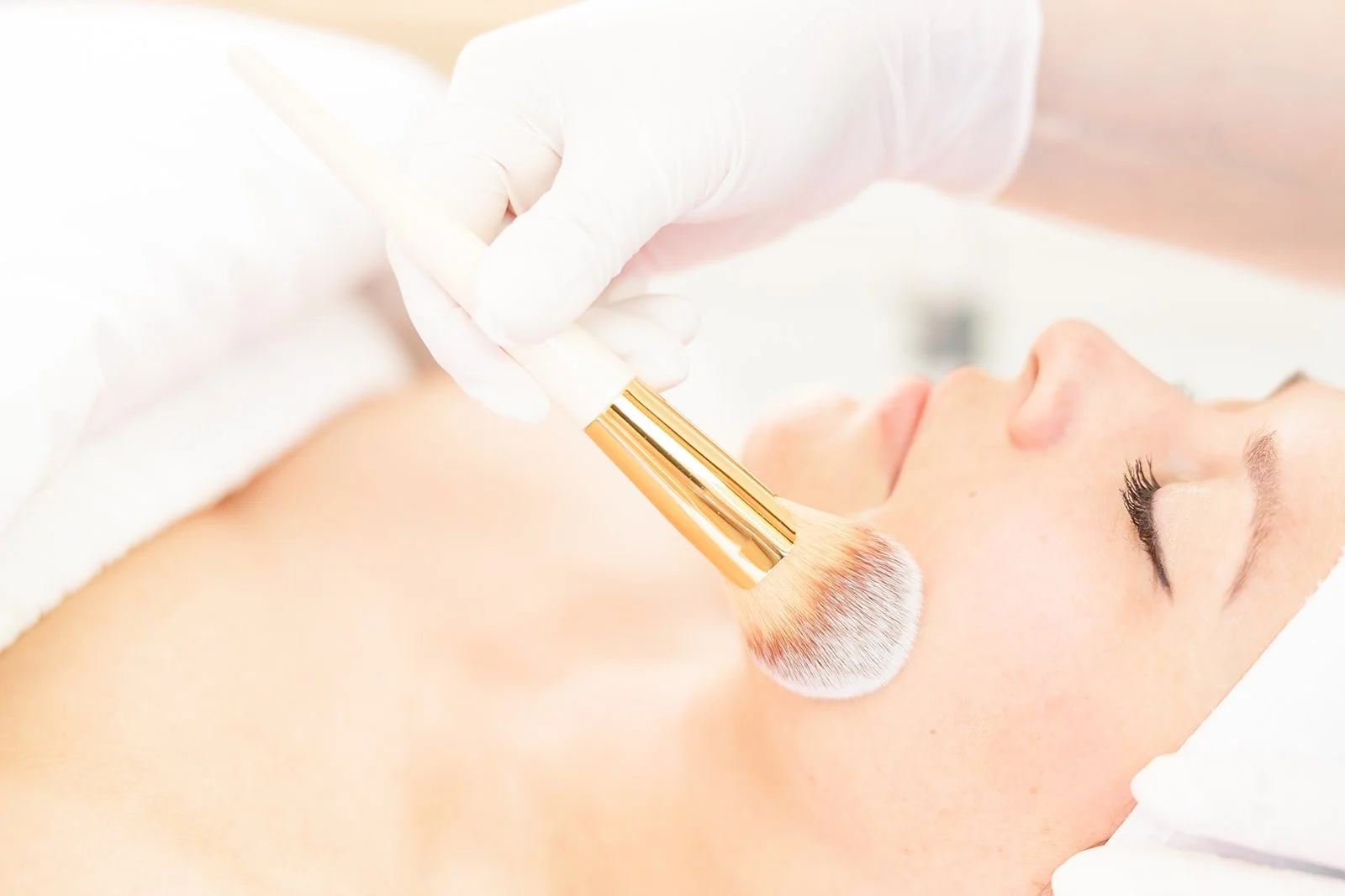 Close-up of a woman receiving a facial treatment with a skincare brush in a med spa.