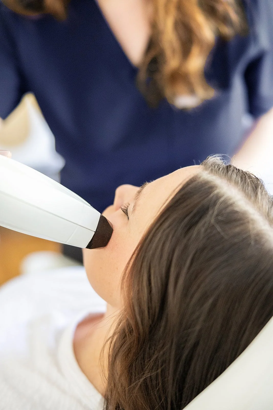 A woman receiving an aesthetics treatment from a med spa.