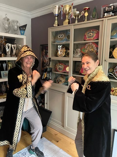 Beth Alford-Sullivan and Katie Taylor in boxing robes in front of a trophy case