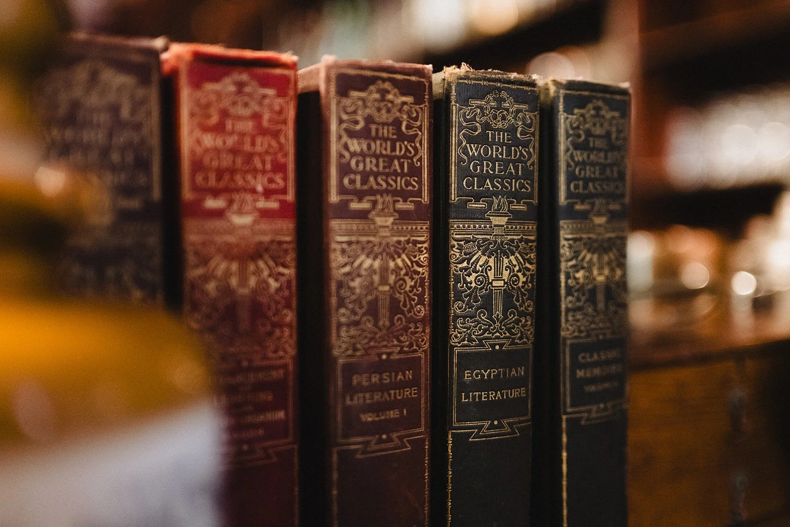A row of vintage books titled 'The World's Great Classics' on a wooden shelf, including volumes on Persian and Egyptian literature.