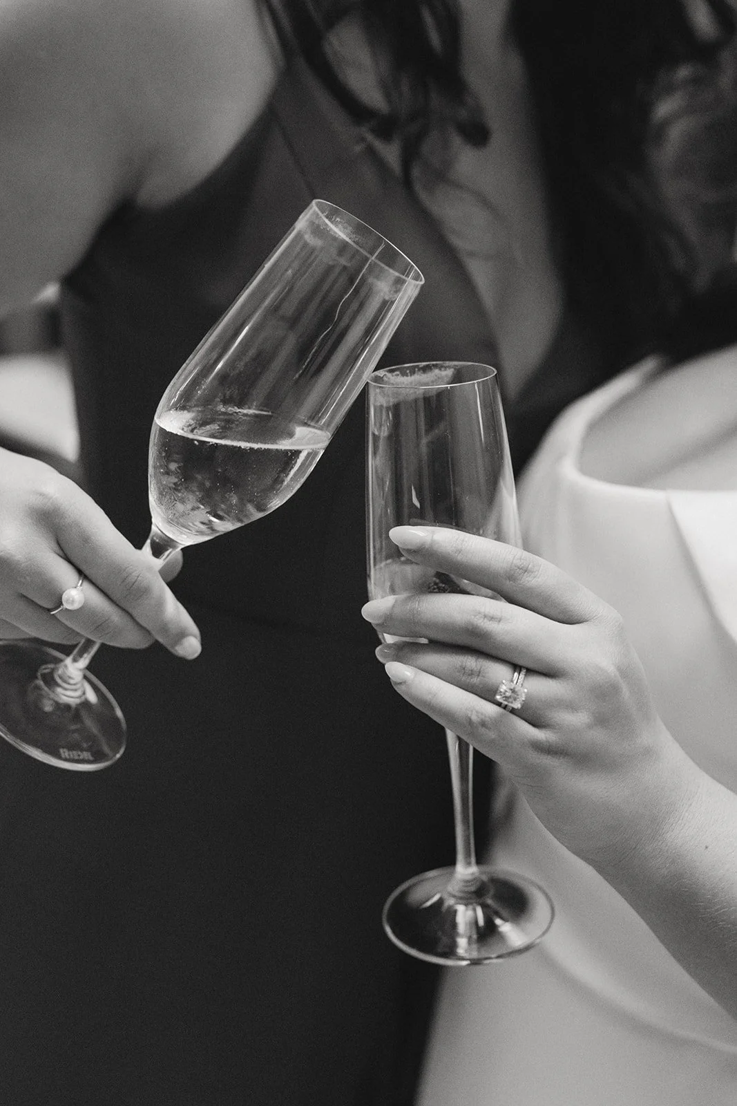 Two women clink glasses of champagne at a celebration or event.