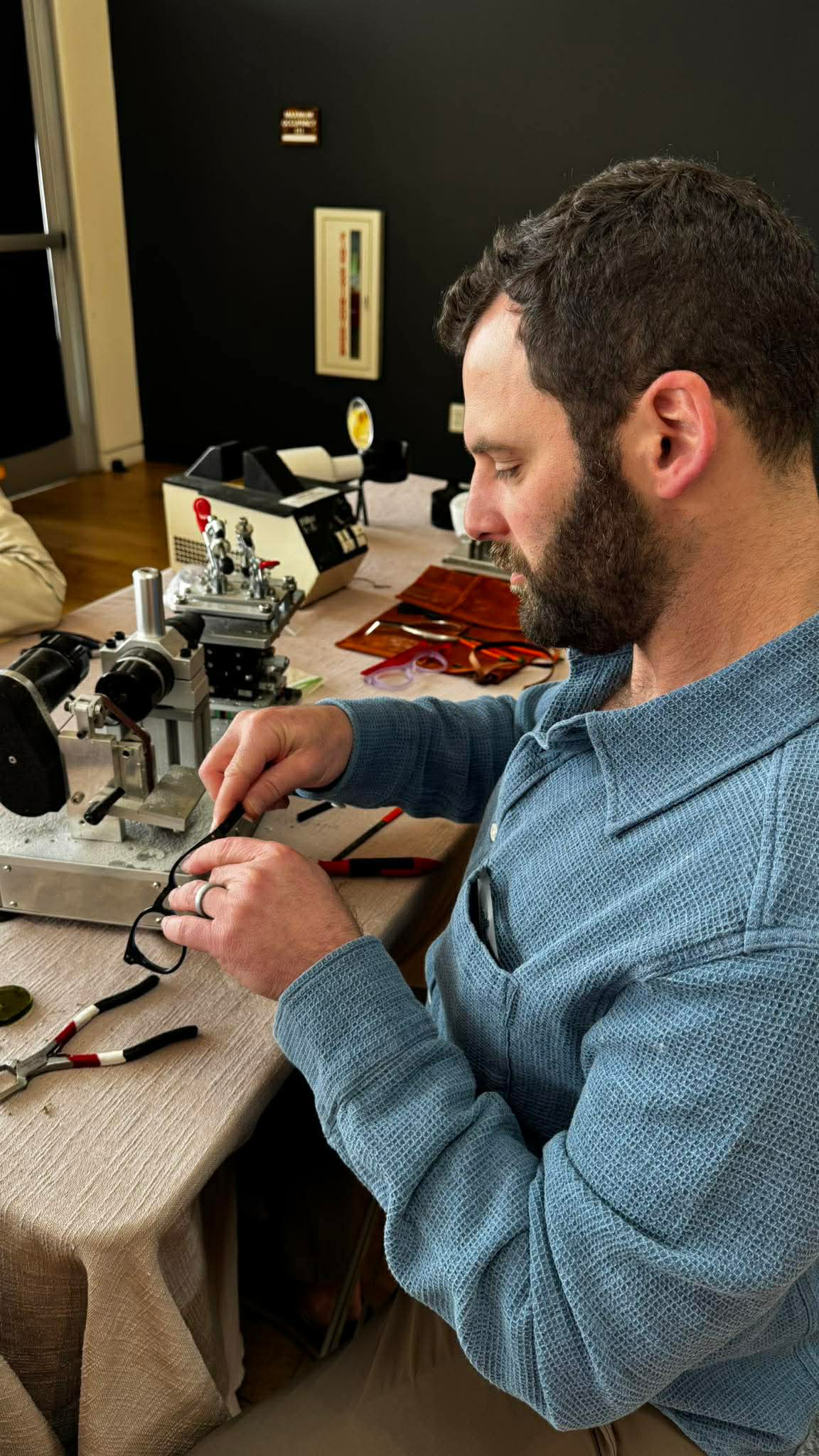 Man working with electronic equipment at a desk, with tools and electronic components around him.