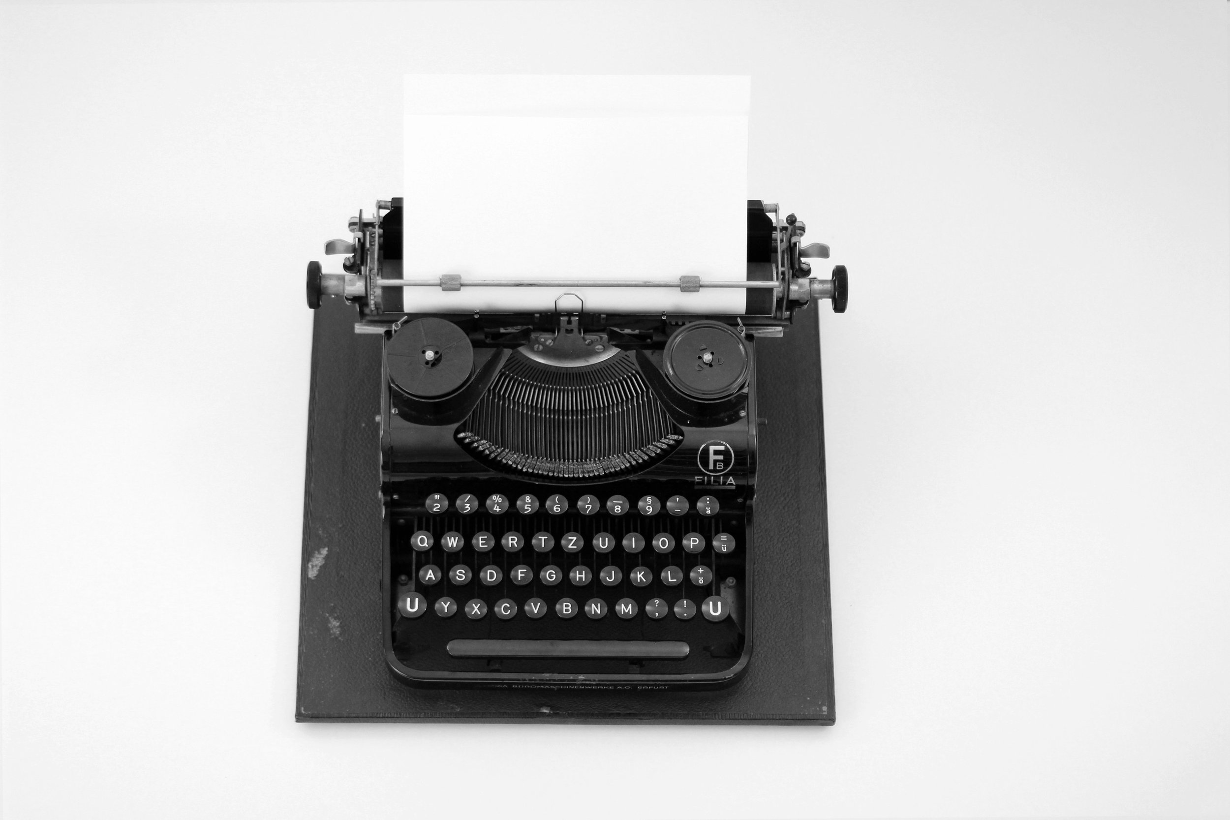A book editor's black vintage typewriter with round keys on a black stand, shown from above against a white background.