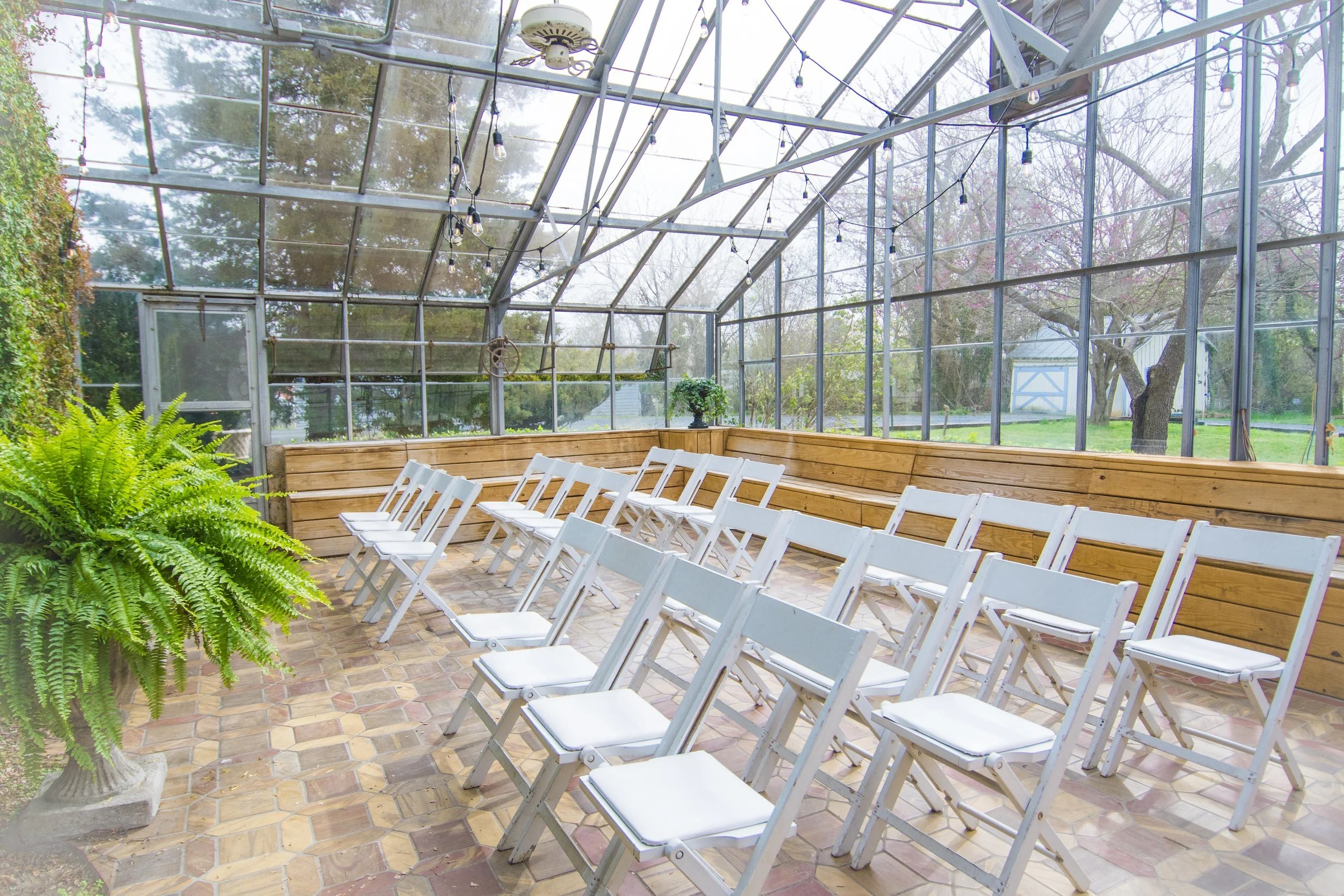 The Greenhouse in daylight: rows of white chairs under the glass roof.